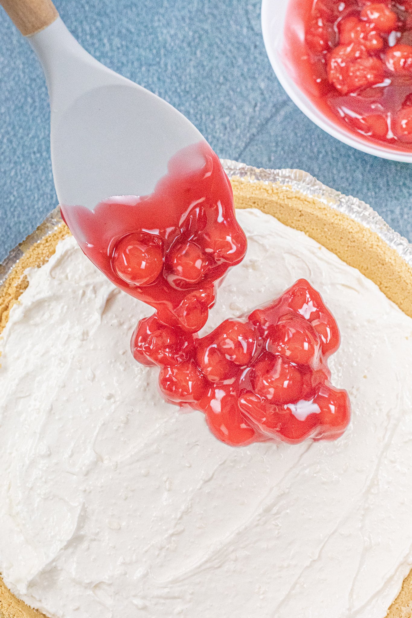 Adding cherry filling to the top of the creamy cheesecake layer