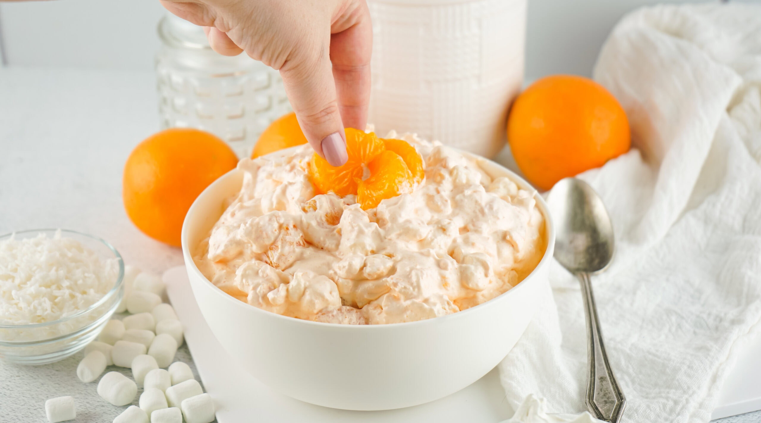 A hand placing a mandarin orange on top of the finished orange fluff