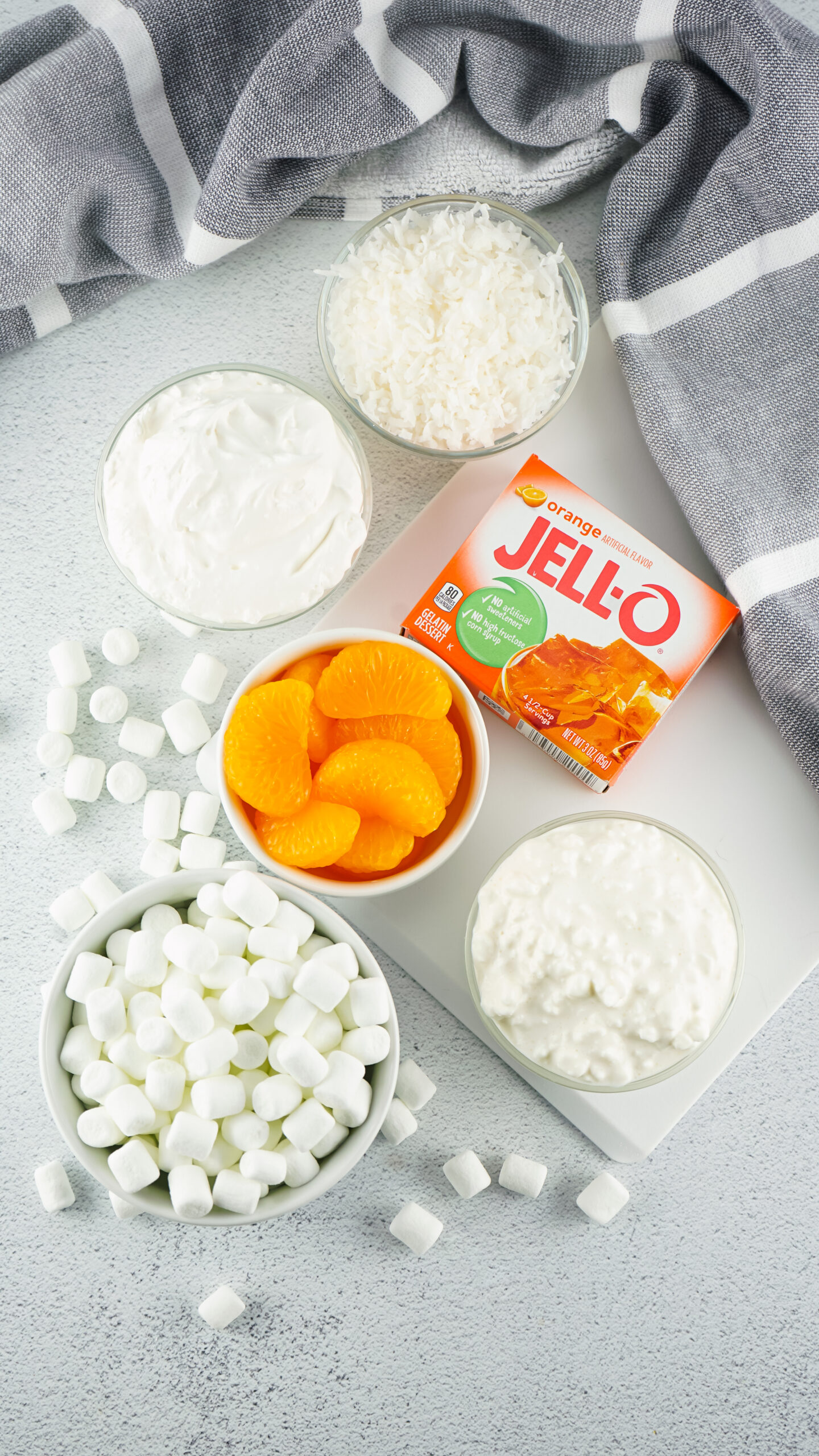 All ingredients are pictured: mandarin oranges, whip cream, marshmallows, cottage cheese, orange gelatin and cottage cheese
