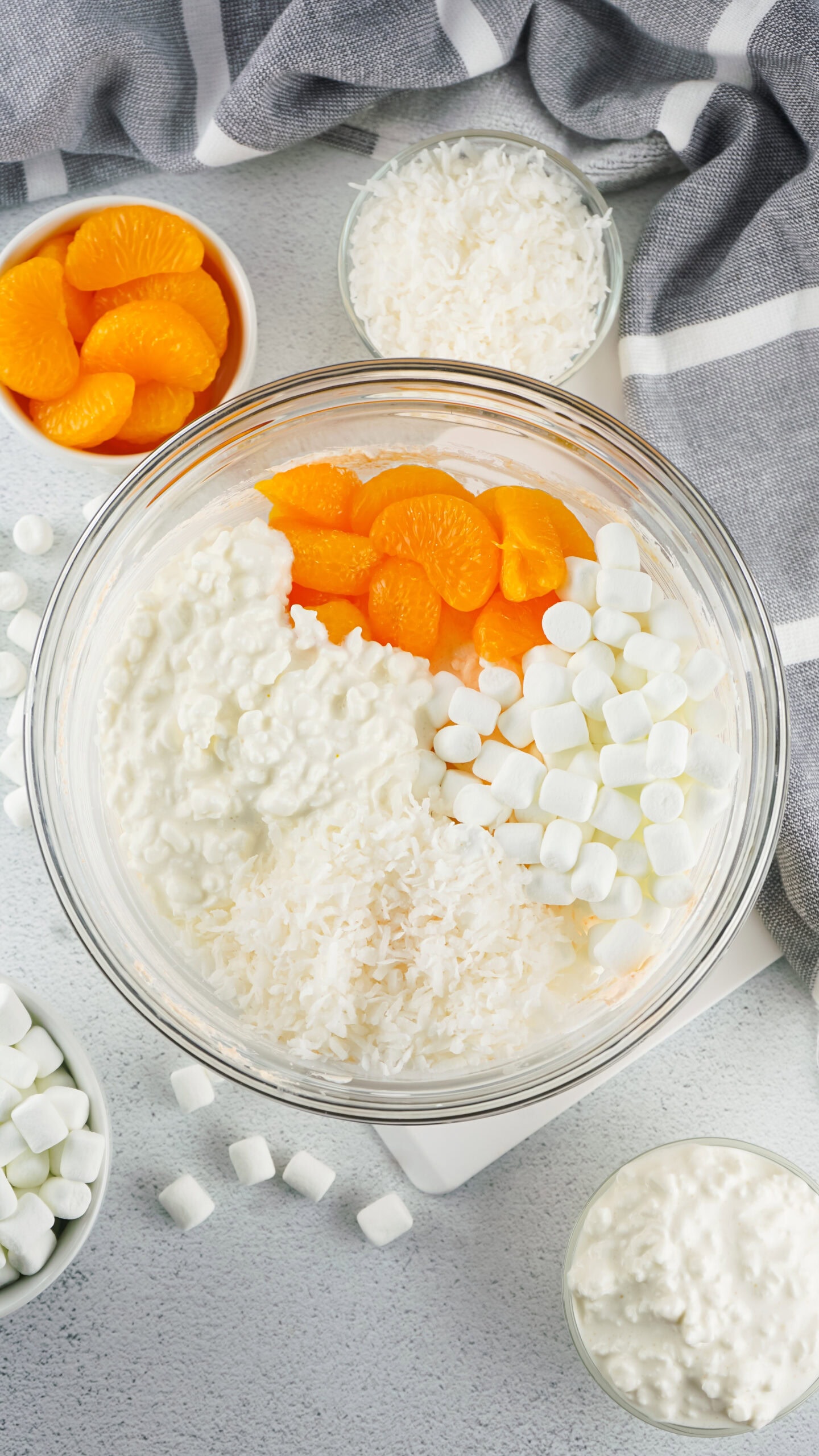 Process of adding mandarin oranges, marshmallows, cottage cheese and shredded coconut in bowl
