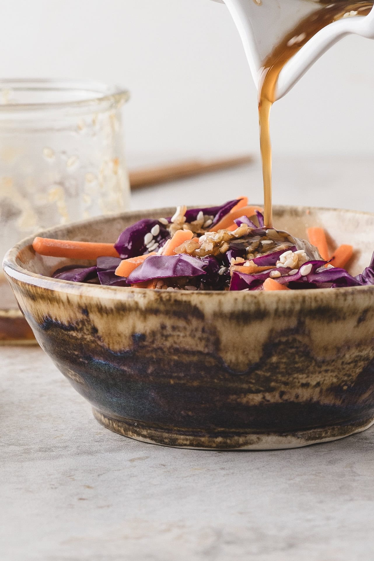 Sesame ginger dressing being poured over a Asian salad.