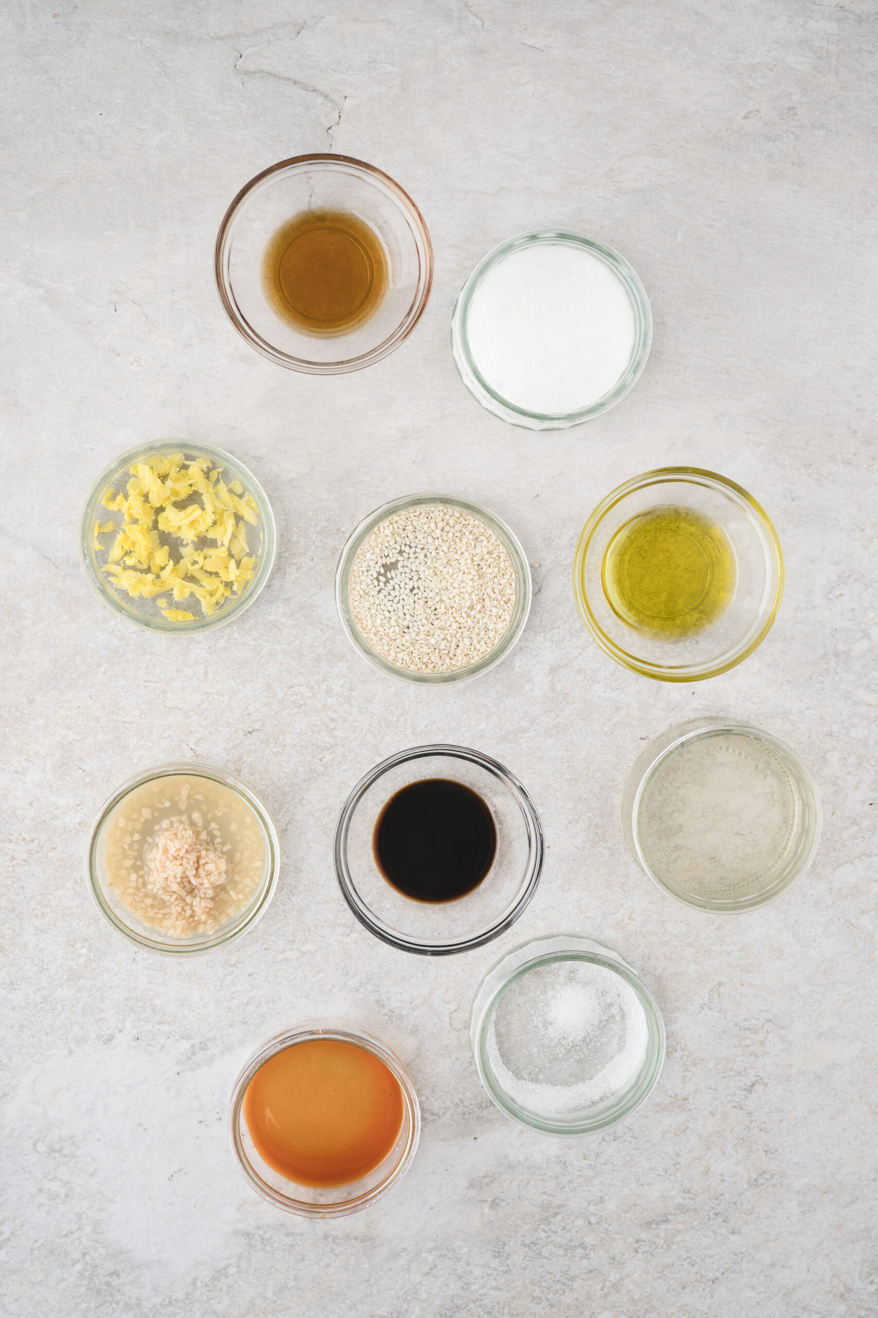 All ingredients pictures: olive oil, sesame oil, rice wine vinegar, sugar, soy sauce, ginger, garlic, salt, sriracha, sesame seeds