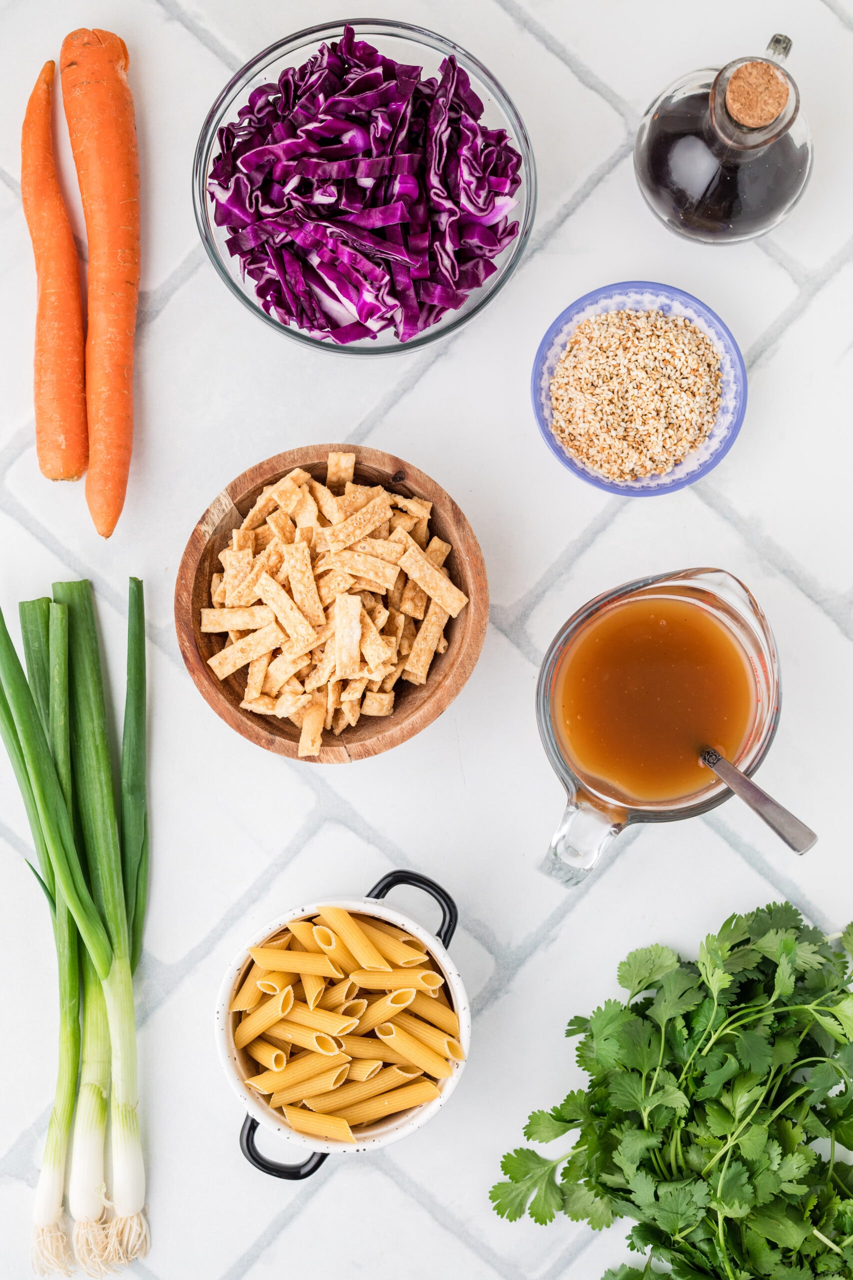 All ingredients pictured: green onion, cilantro, pasta, fried wontons, soy sauce, toasted sesame seeds, carrots, red cabbage
