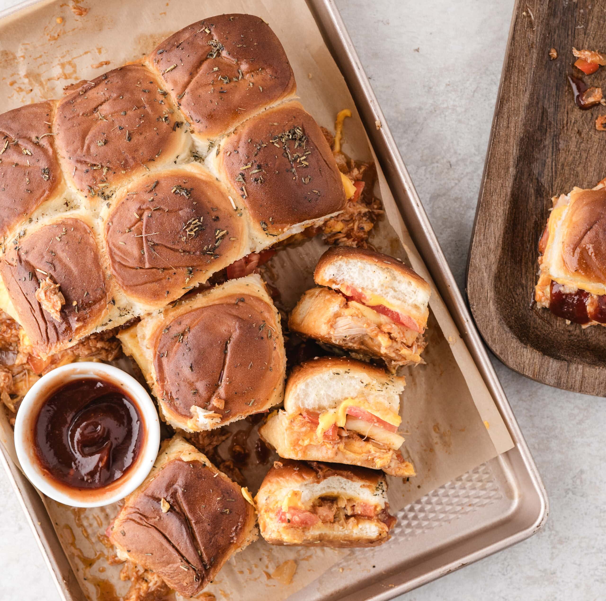 BBQ chicken sliders are all baked and ready to be enjoyed. Several sliders are turned up on its side to see its texture of the layers