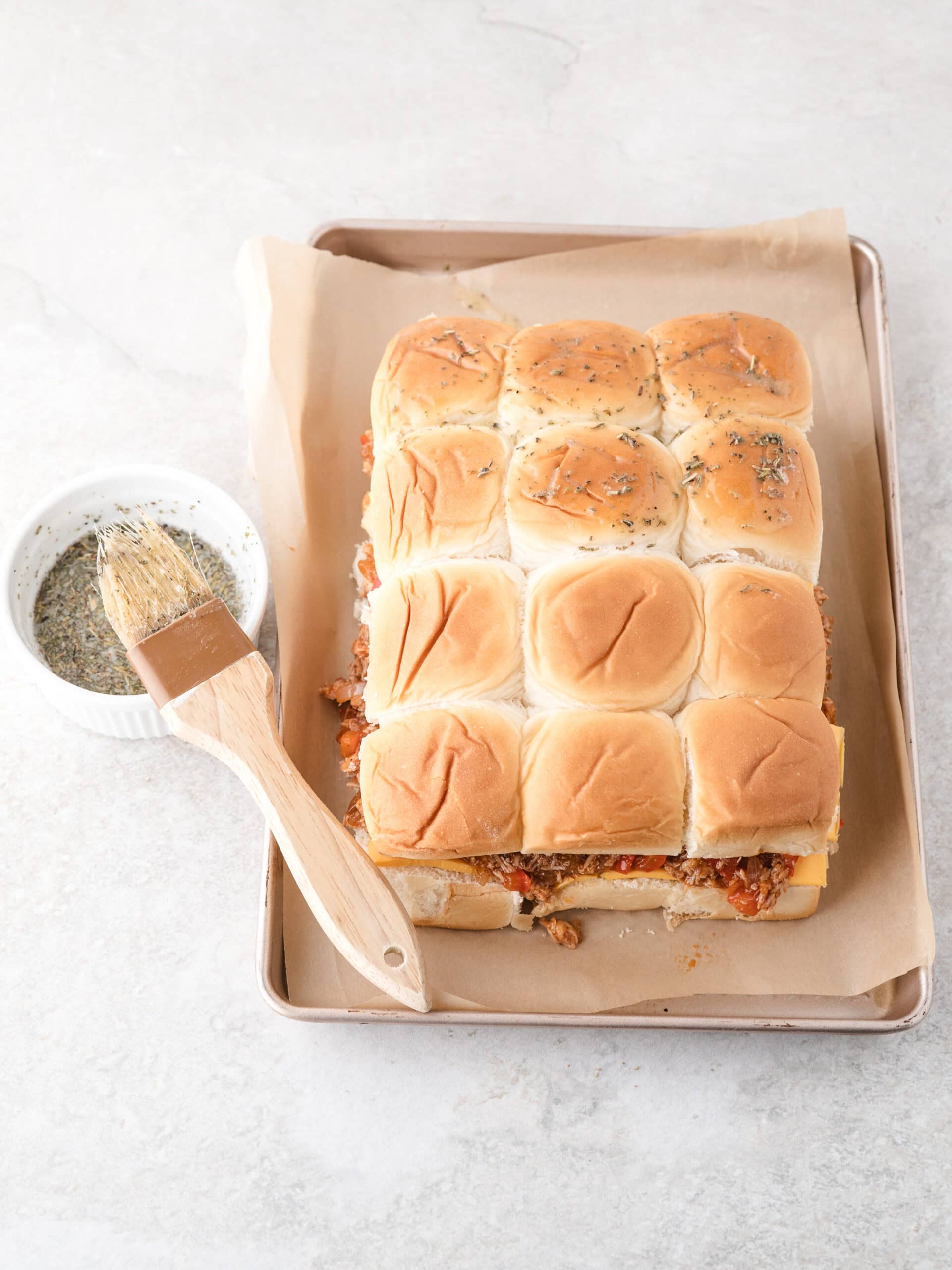 Process of melting the butter in a small bowl and add Italian seasoning and 4 cloves of garlic (pressed). After that is mixed together, brushing the tops of the buns with the butter.