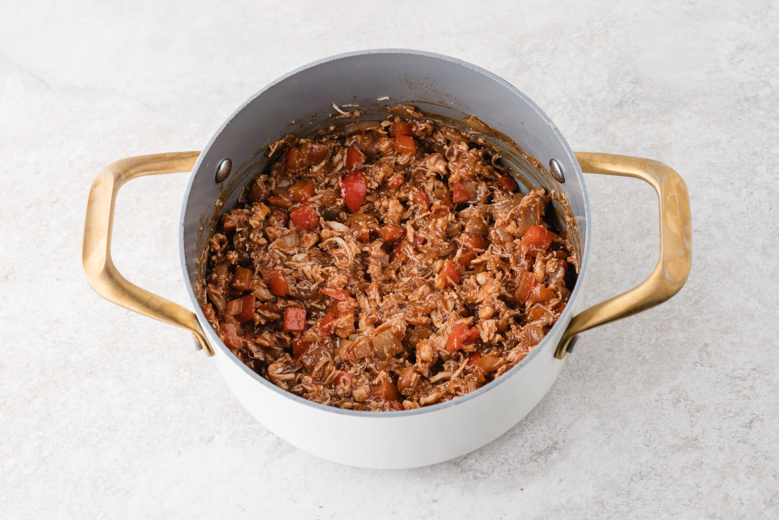 Completing the BBQ chicken mixture: by adding bbq sauce in the chicken, diced tomatoes, onion and red pepper.