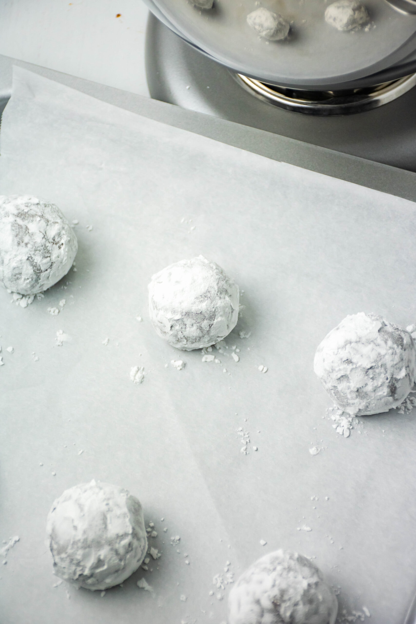 Brownie crinkle cookies being rolled powdered sugar