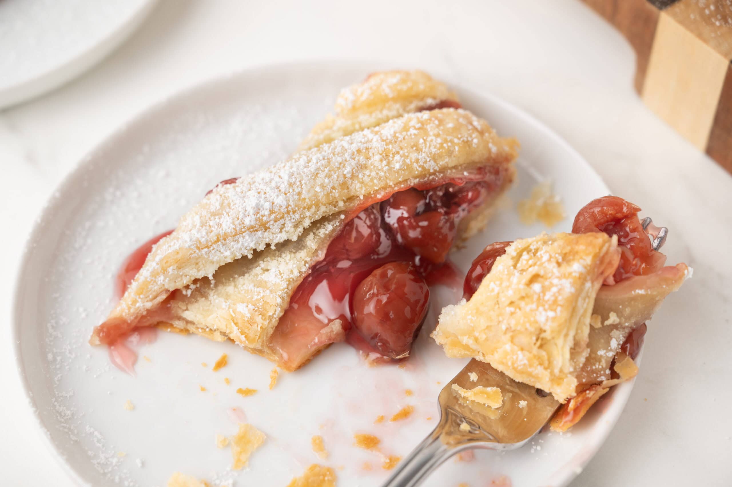 Cherry strudel on a plate, cut into a bite size bit on a fork