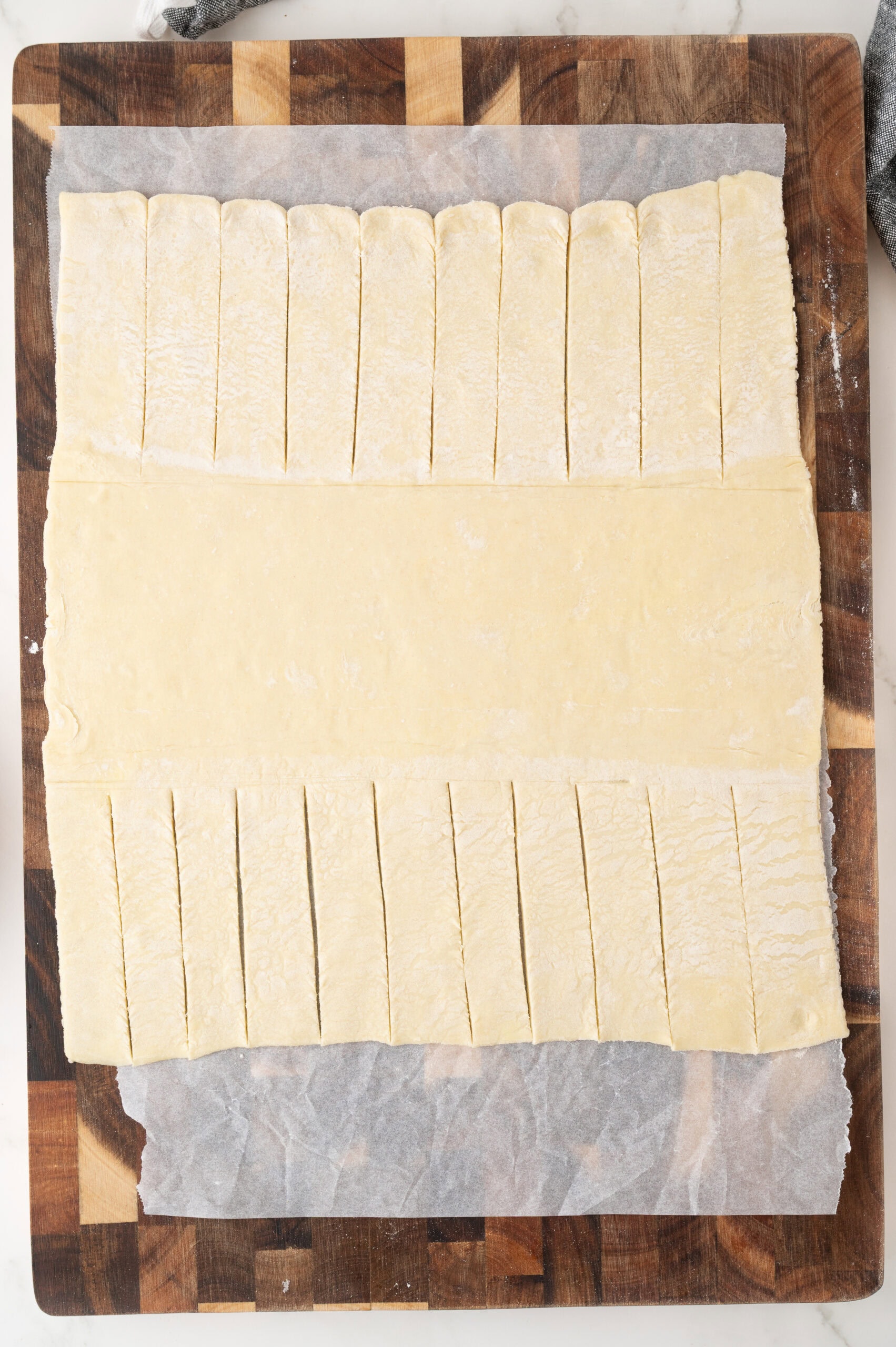 Starting the process of creating the cherry strudel by cutting sections into the puff pastry