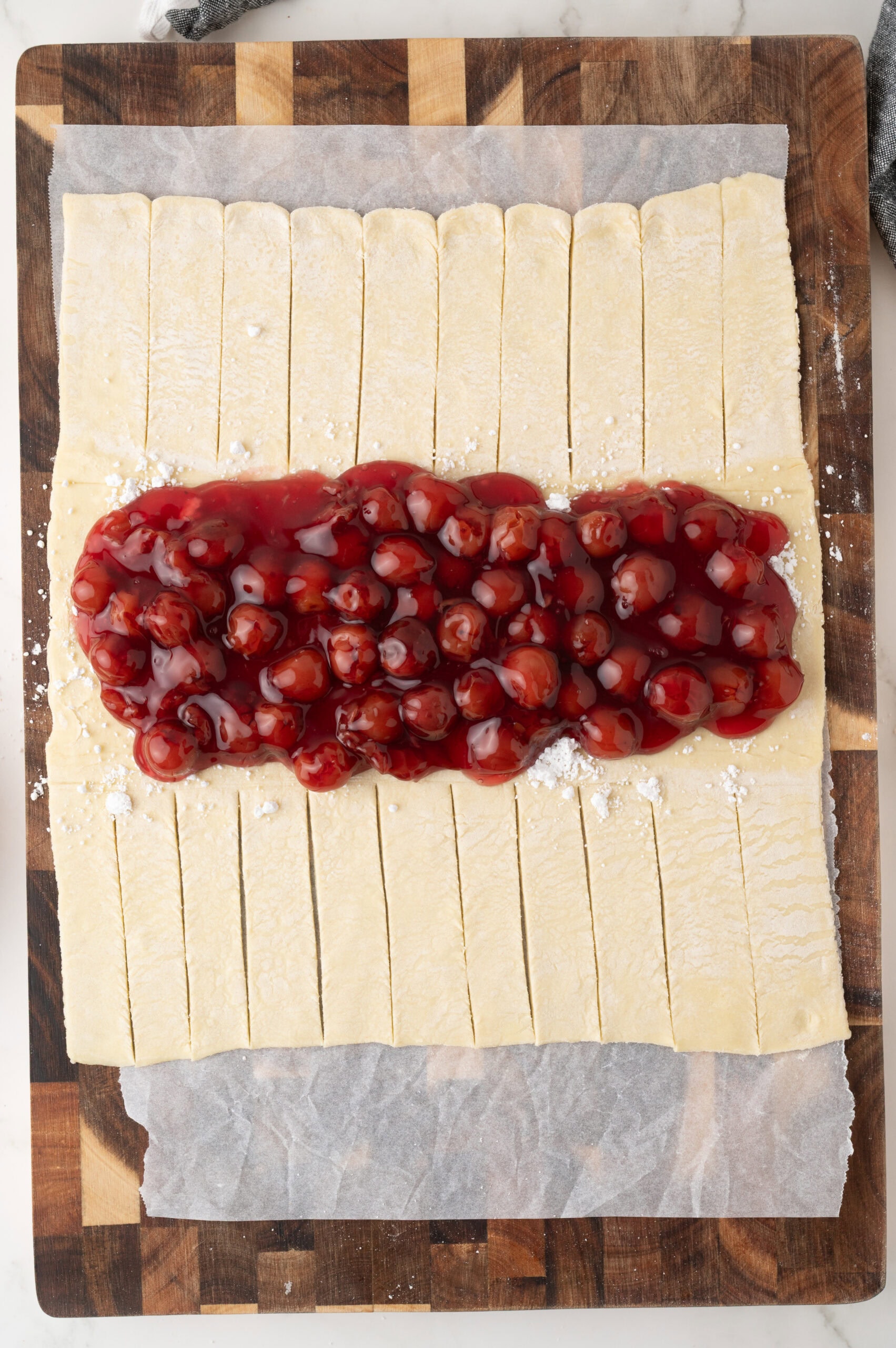 The process of adding the cherry pie filing to the middle of the puff pastry