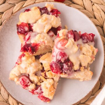 three cranberry crumble bars with powdered sugar glaze