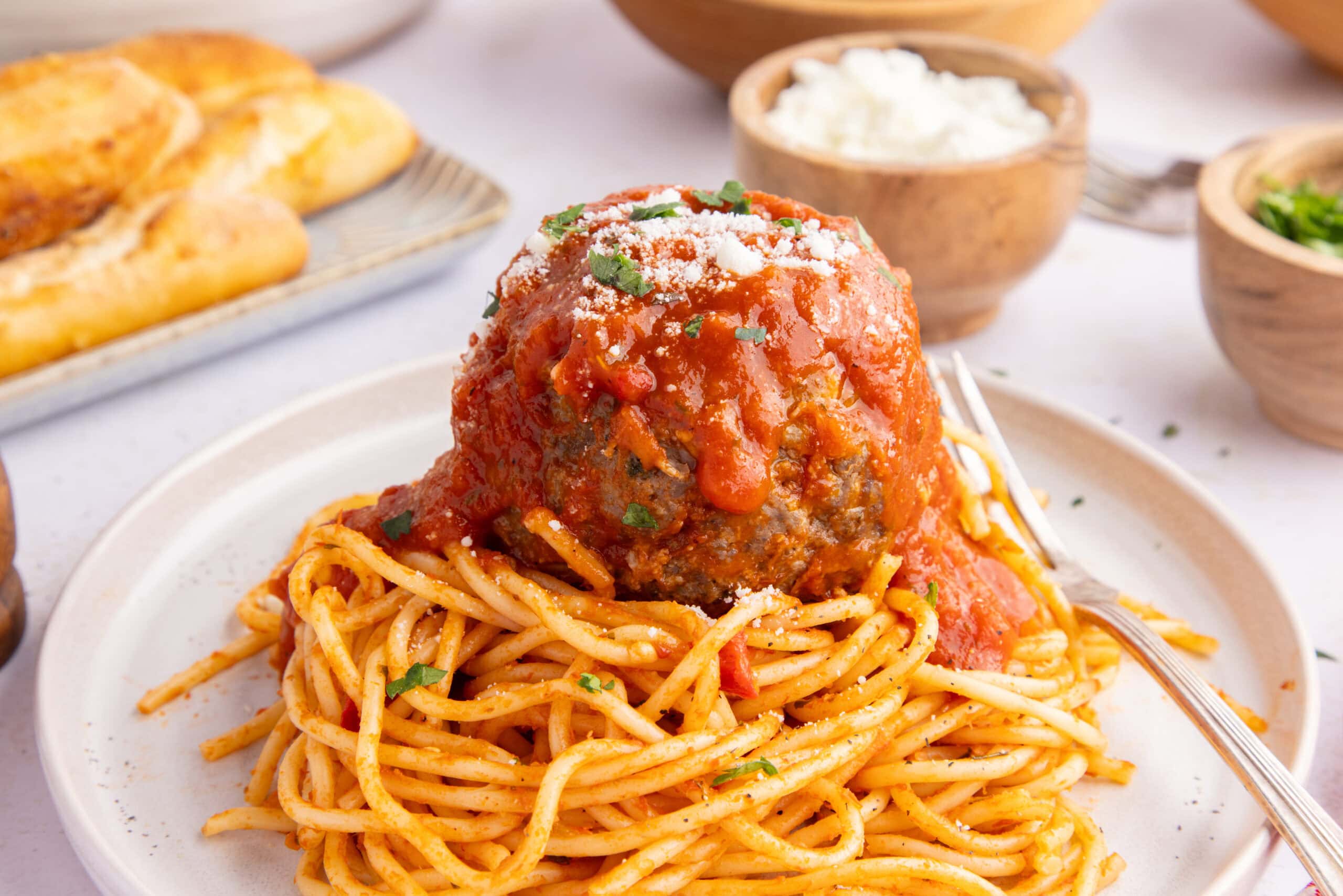 Jumbo mozzarella meatball on top of a plate of spagehetti.