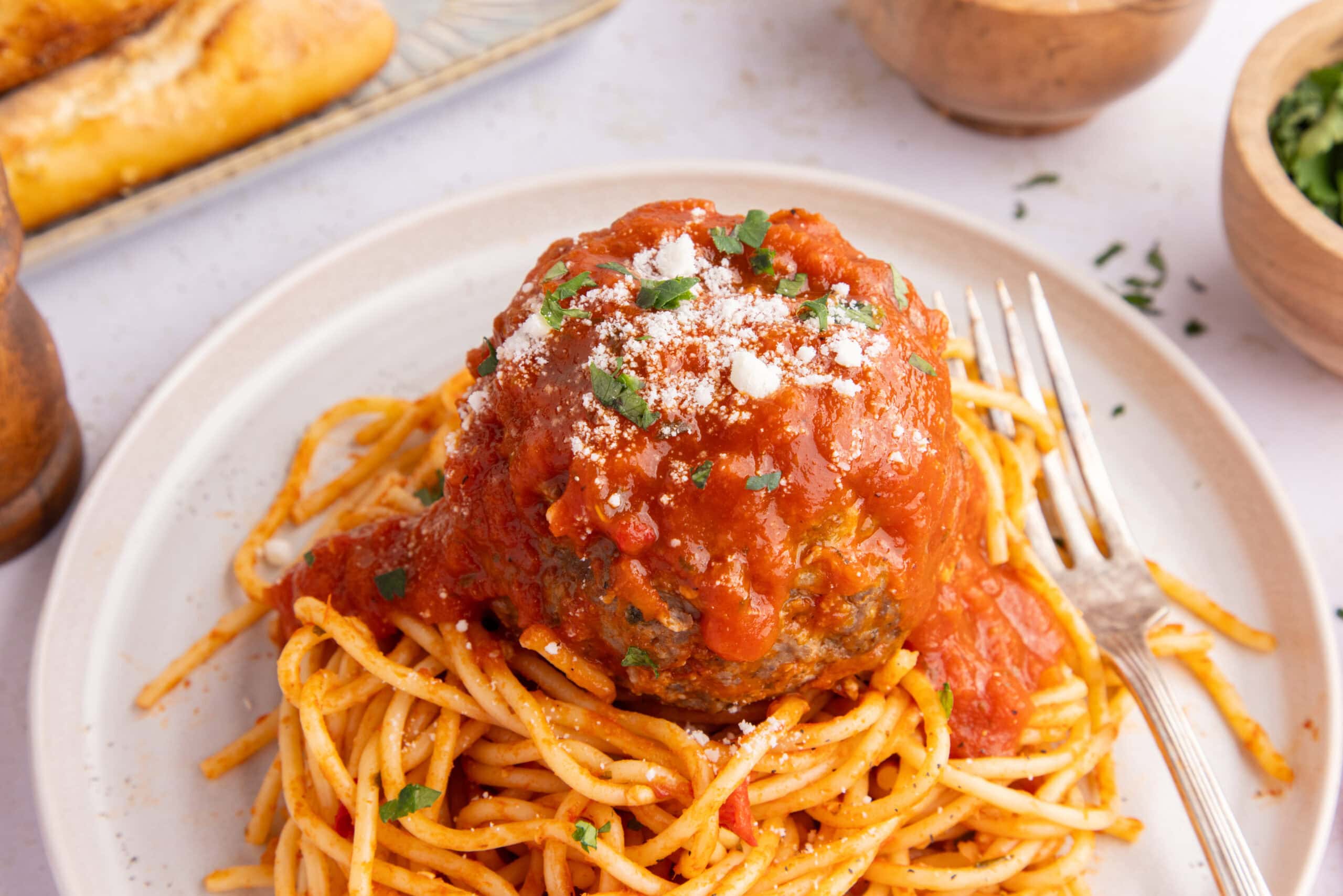 Jumbo mozzarella stuffed meatball, on top of a plate of spagehetti.