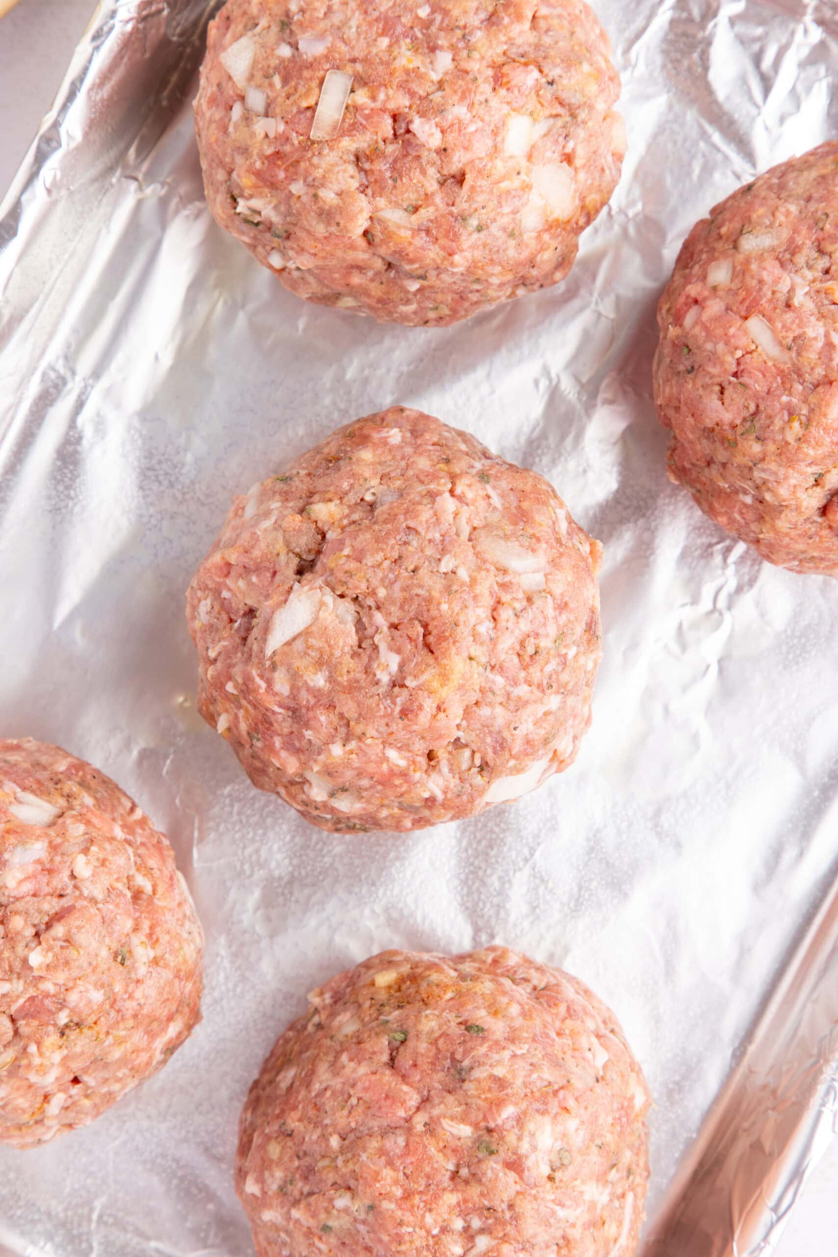 Mozzarella cheese has been added inside, the meatballs are not back to being rolled up and place on a baking pan