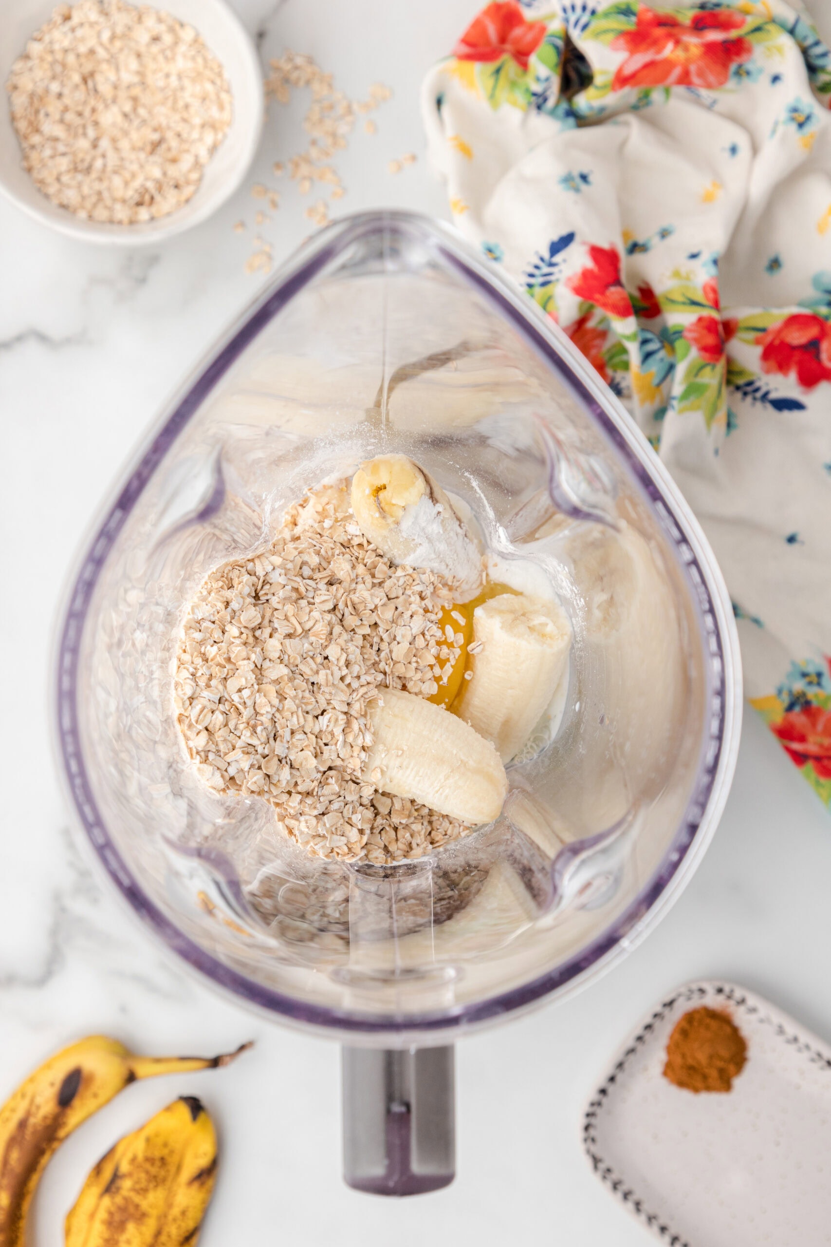 The process of adding bananas, rolled oats, milk and vanilla