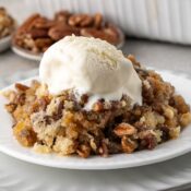 pecan pie cobbler topped with vanilla ice cream on a white plate