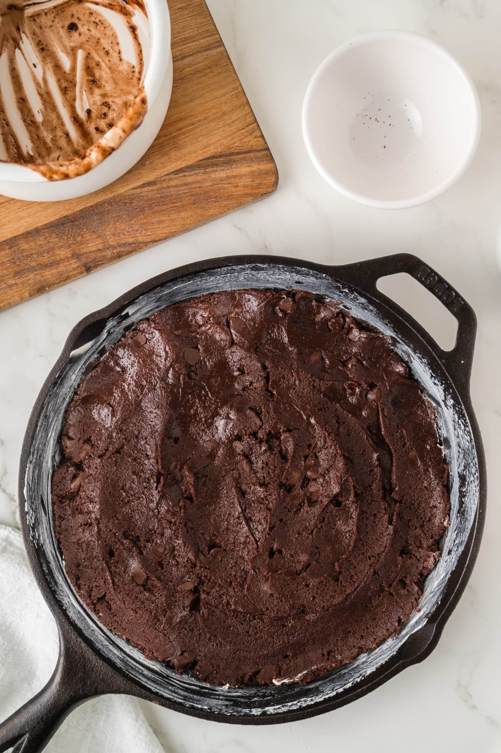 The process photo of adding the brownie batter to a well-buttered skillet, ready to be baked