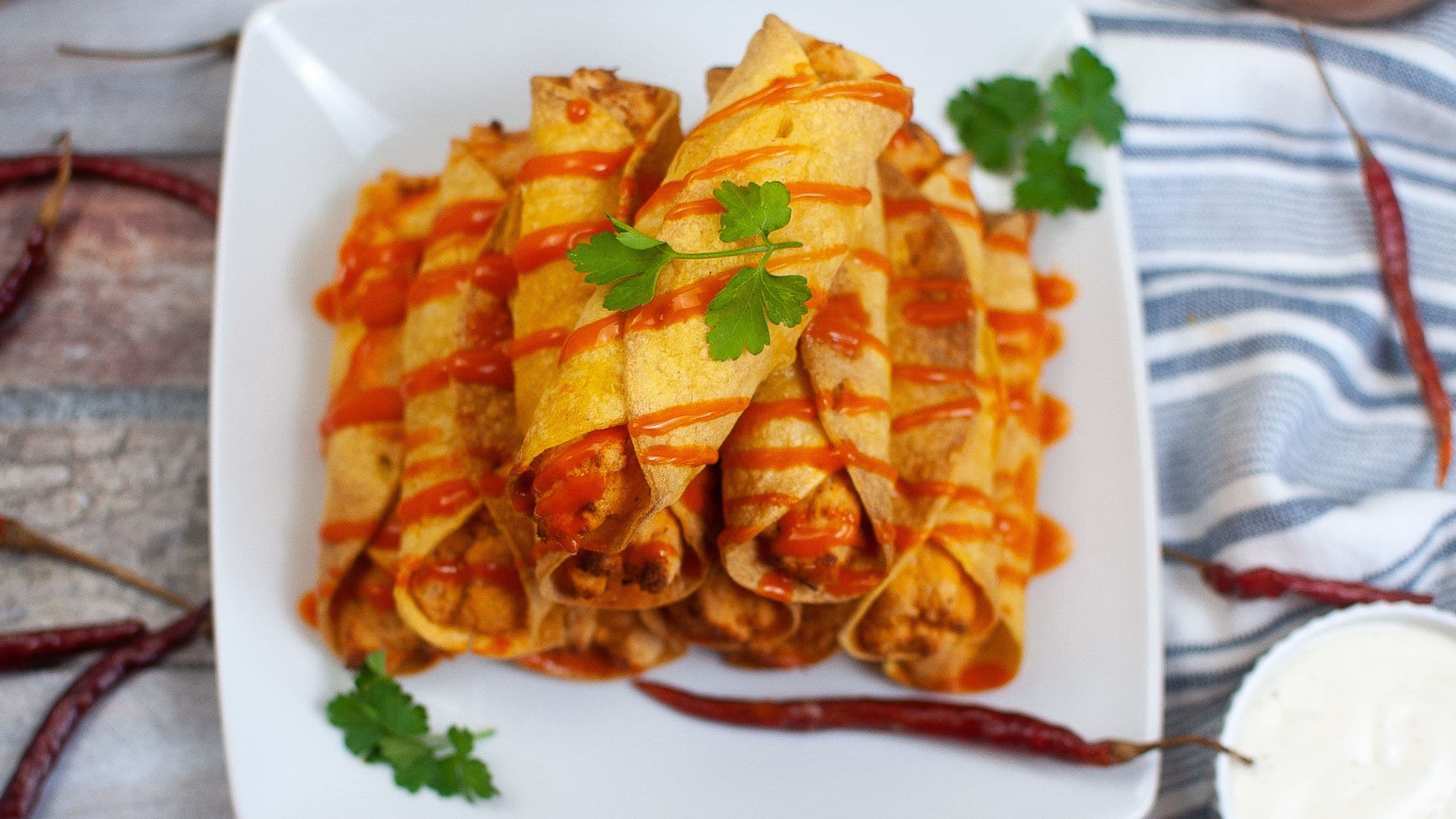 A stack of air fryer buffalo chicken taquitos on a plate, ready to be enjoyed