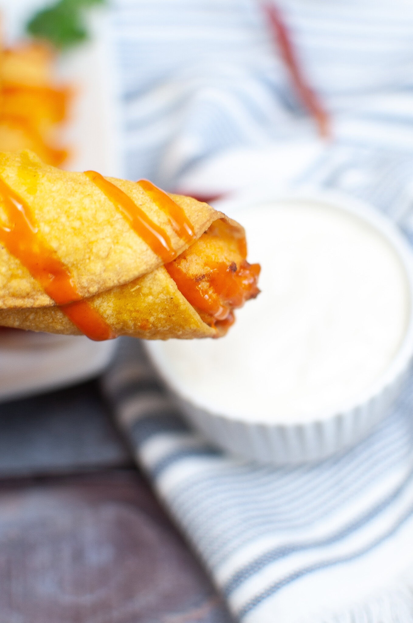 One buffalo chicken taquito with hot sauce on top ready to be dipped in ranch