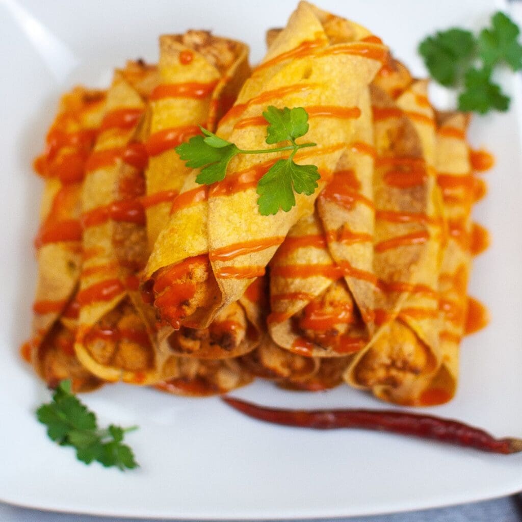 A plate of air fryer buffalo chicken taquitos stacked up, ready to be enjoyed