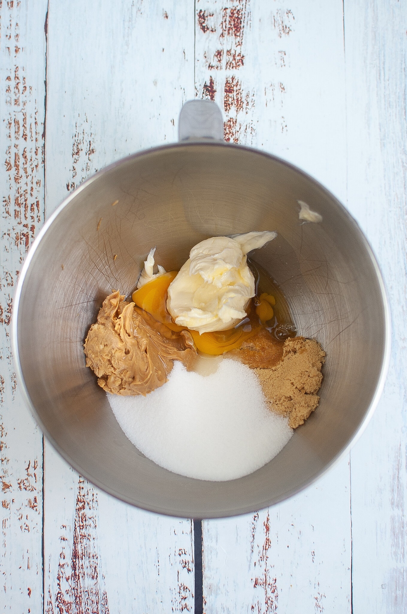 All wet ingredients in a mixing bowl: sugars, egg, peanut butter