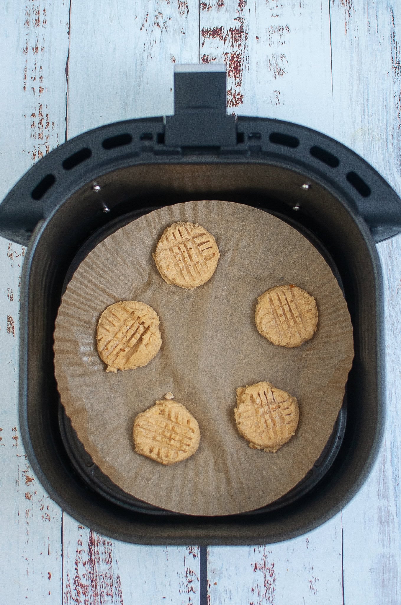 Cookie dough placed with space apart to cook, pressing a fork down in sugar to create lines