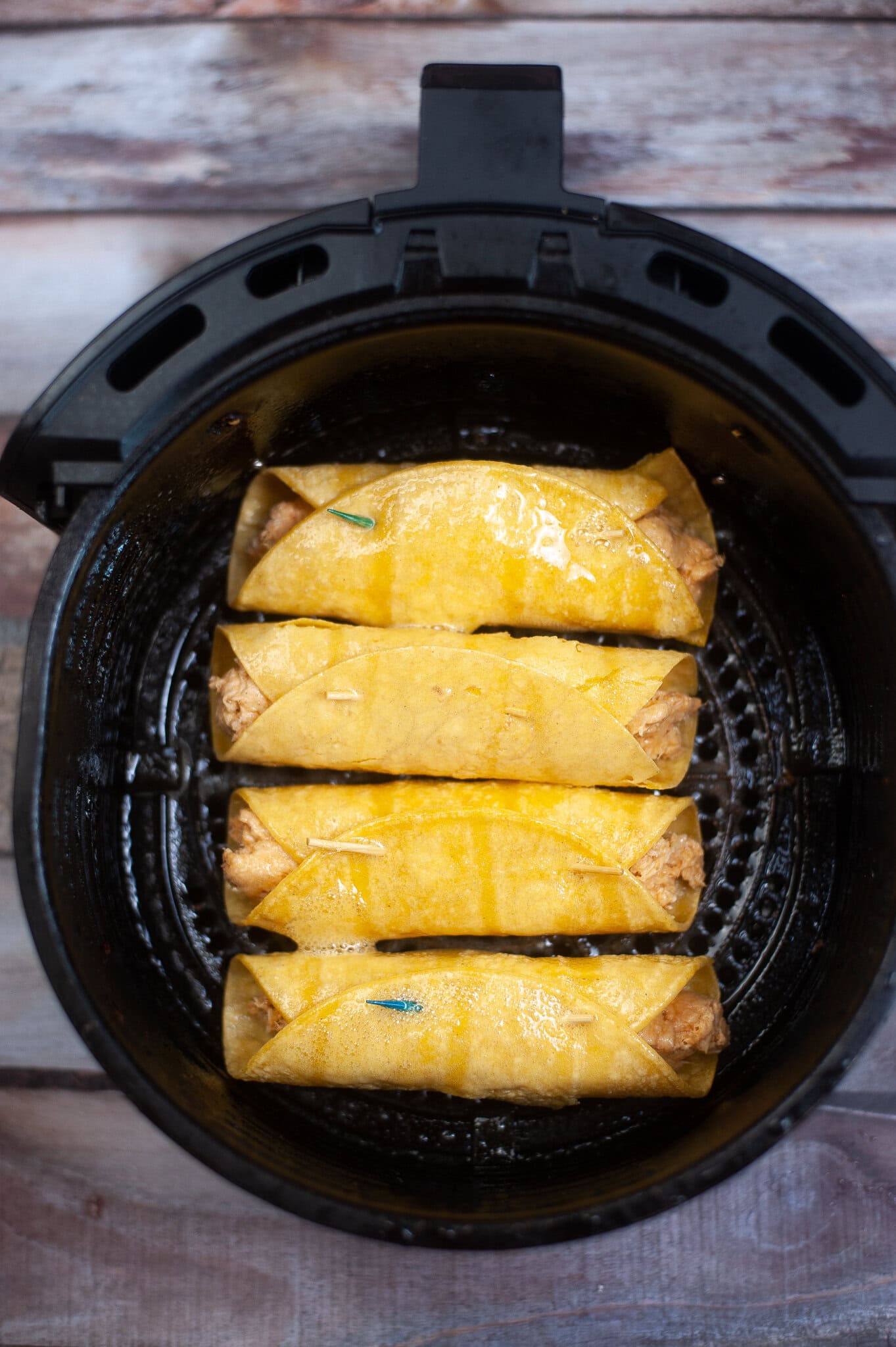 Chicken taquitos are ready to be air fried. The chicken mixture is rolled up in a corn tortilla and placed in air fryer