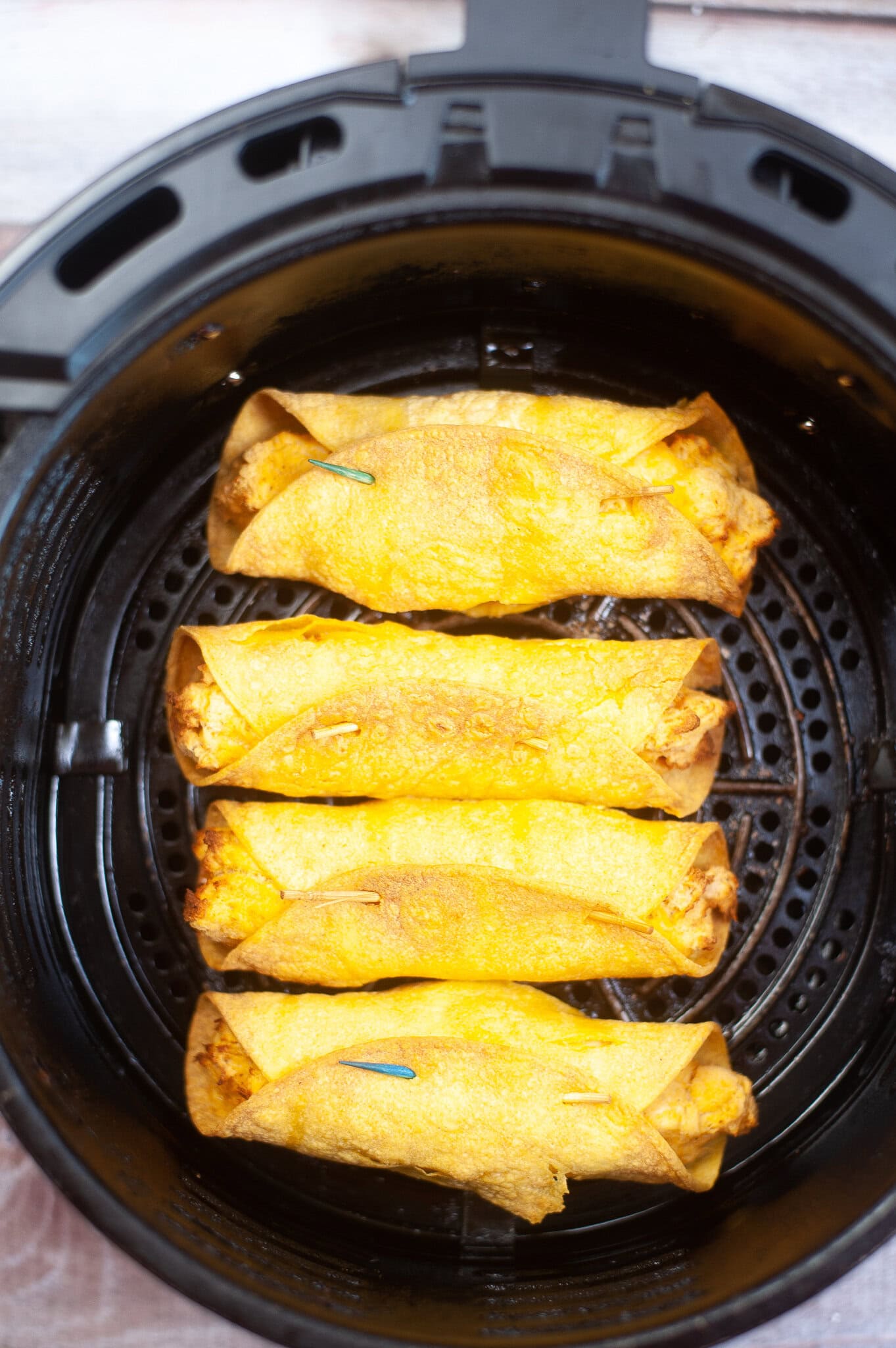 Chicken taquitos in the air fryer, all cooked and ready to be cooled and add a drizzle of buffalo sauce