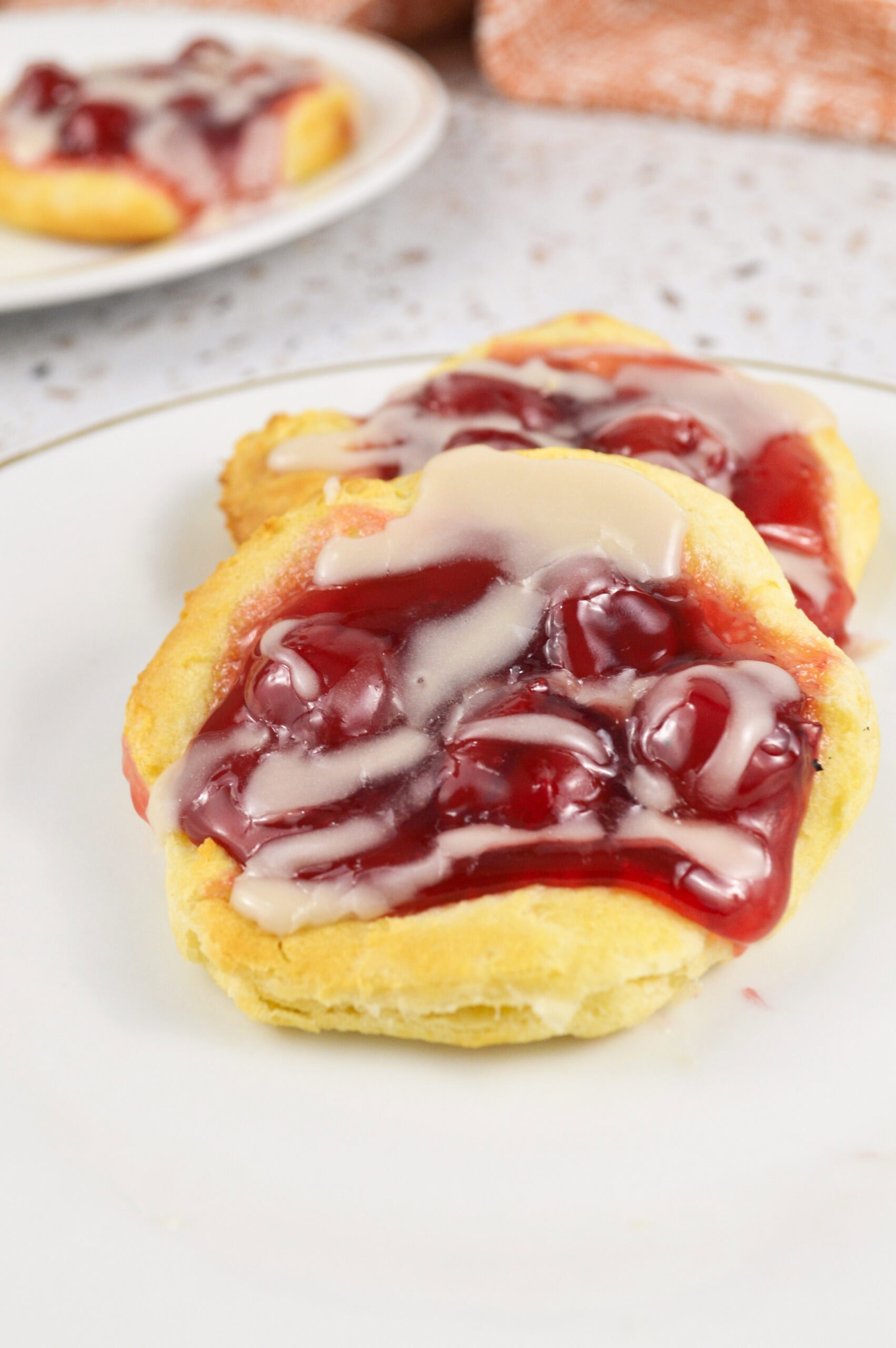 Plated cherry danishes with almond glaze, ready to be enjoyed