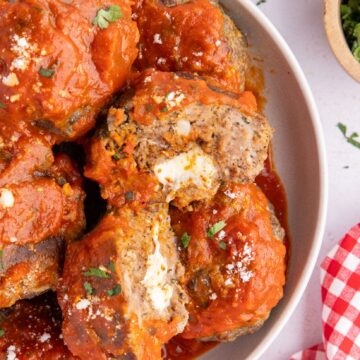 Jumbo stuffed mozzarella stuffed meatballs in a plate, cut in half to see the cheese