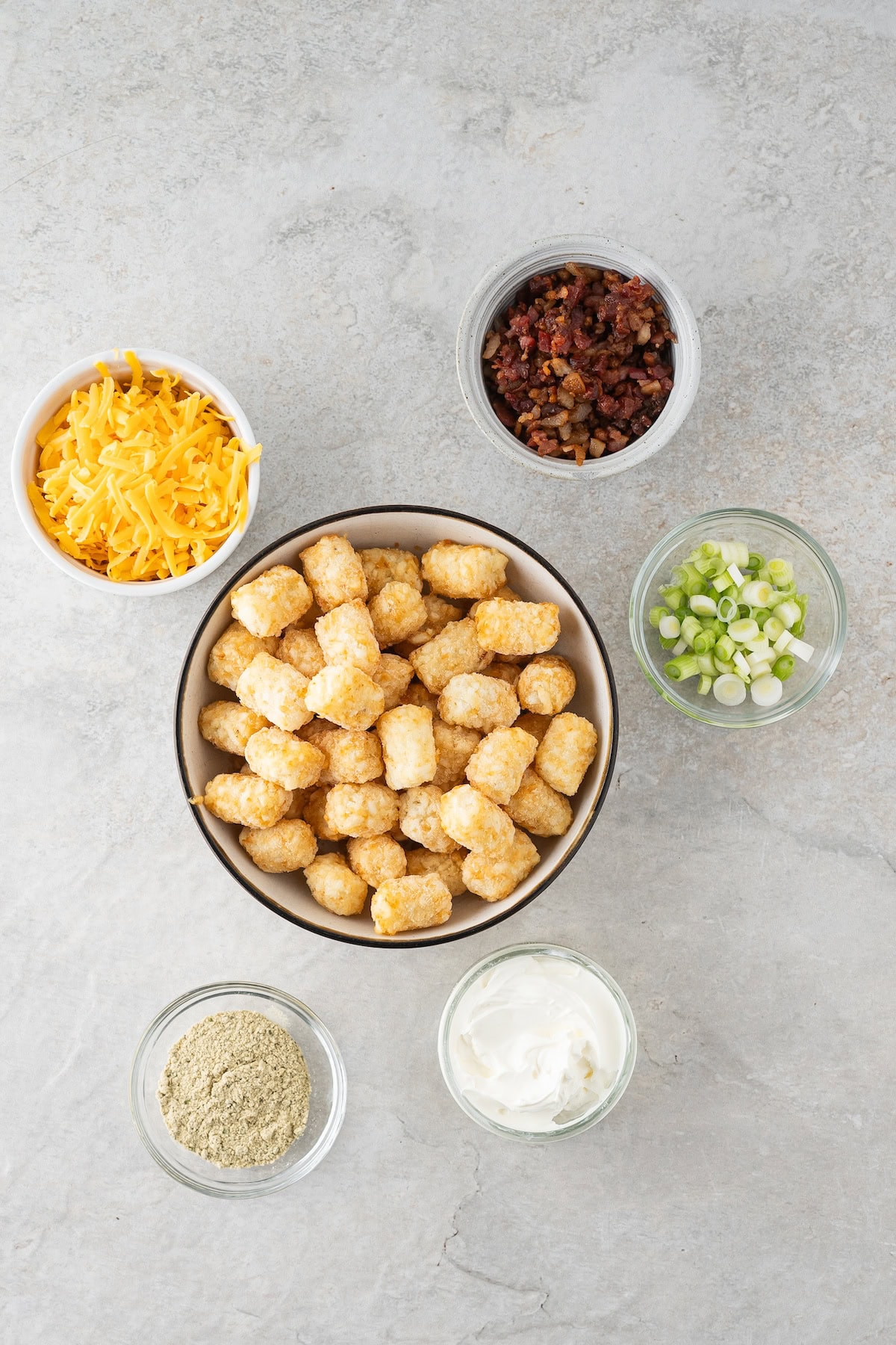 loaded tator tots ingredients including shredded cheddar cheese, crumbled bacon, and ranch seasoning