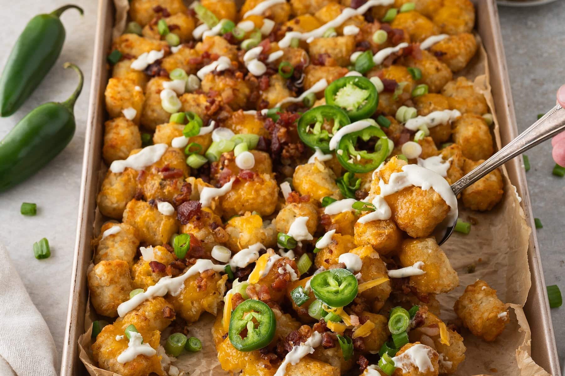 a spoonful of loaded cheesy tater tots with ranch sour cream
