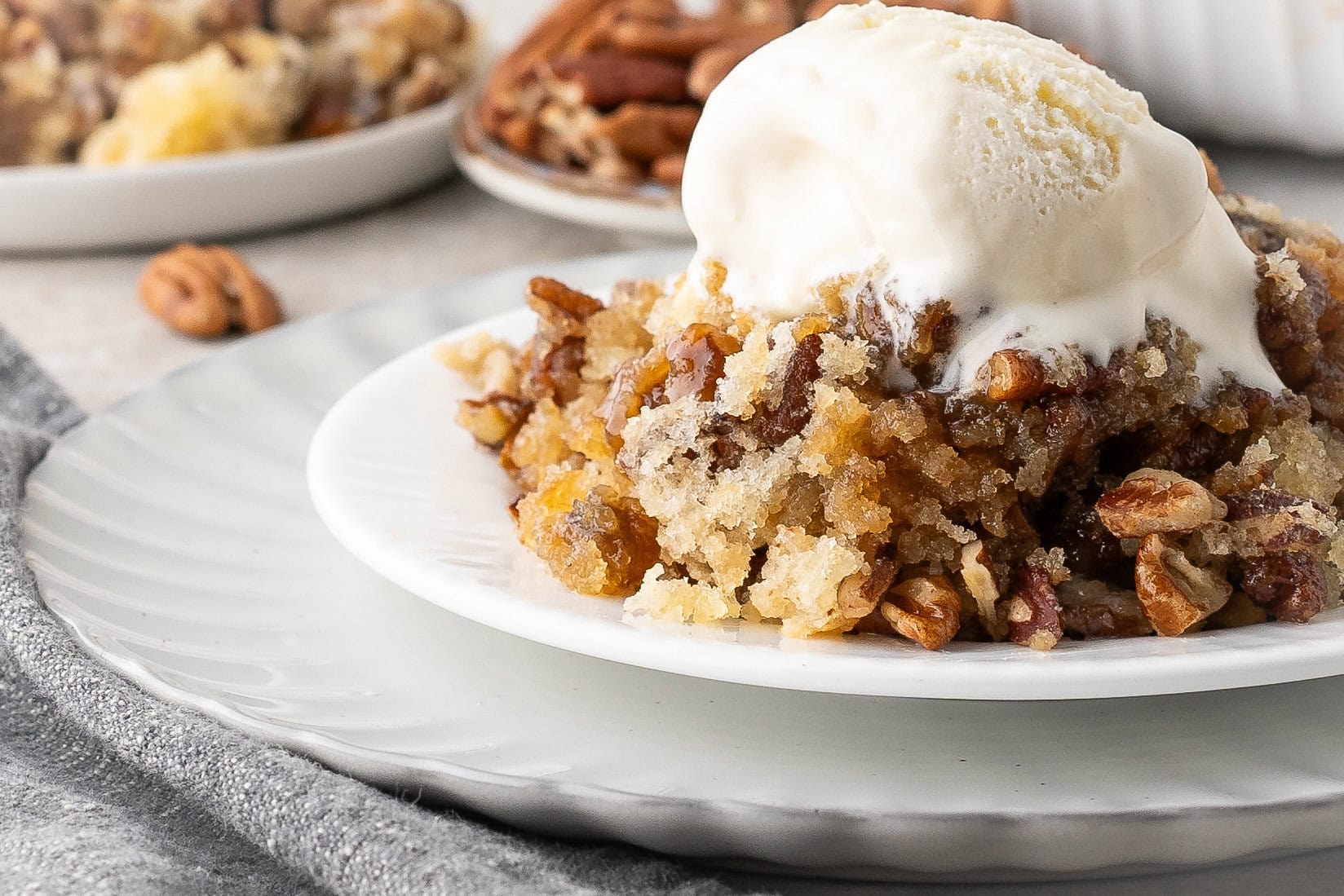 Close up plated pecan pie cobbler with vanilla ice cream on top