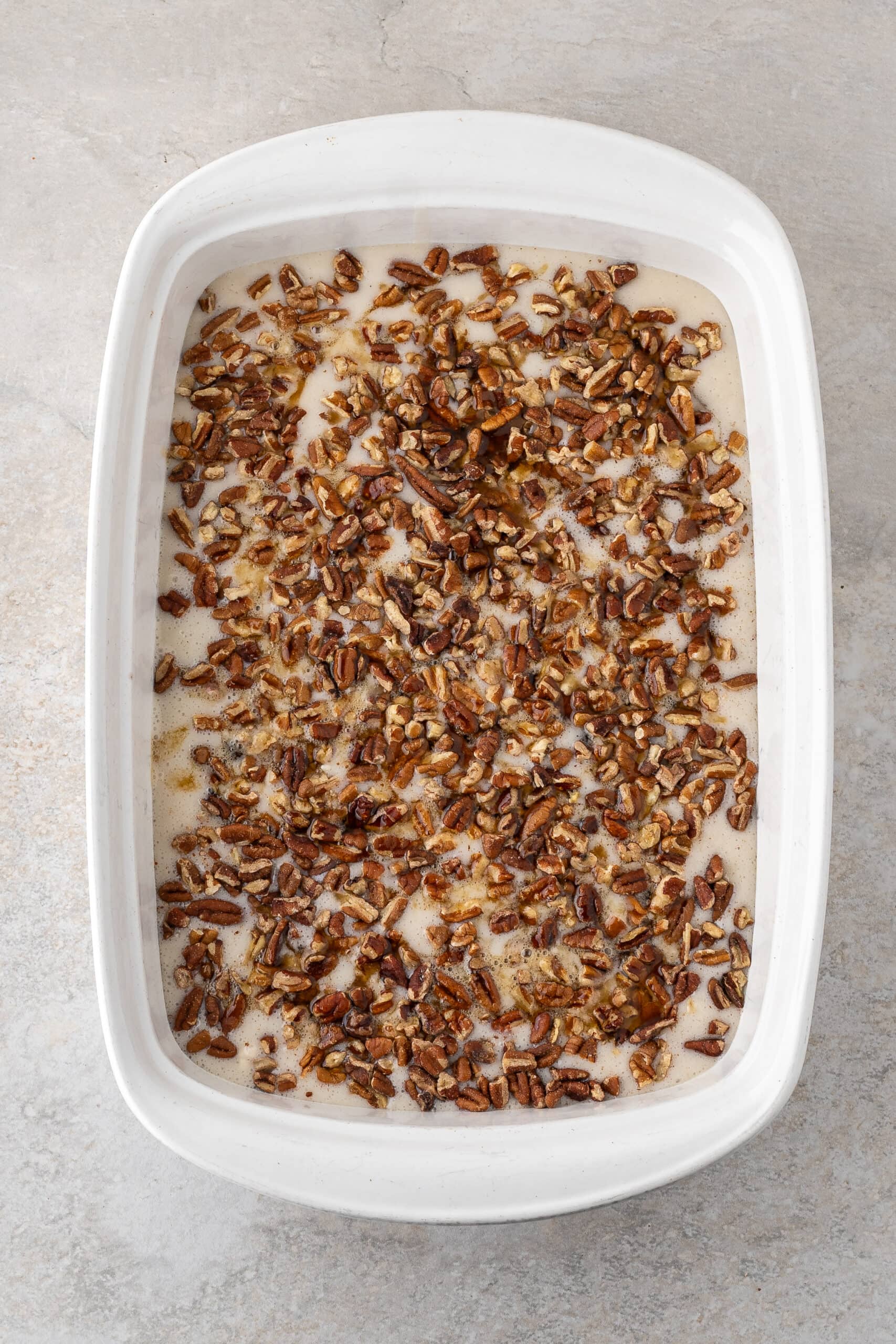 Pecan pie cobbler with all its ingredients in a 9x13 baking dish, ready to go into the oven