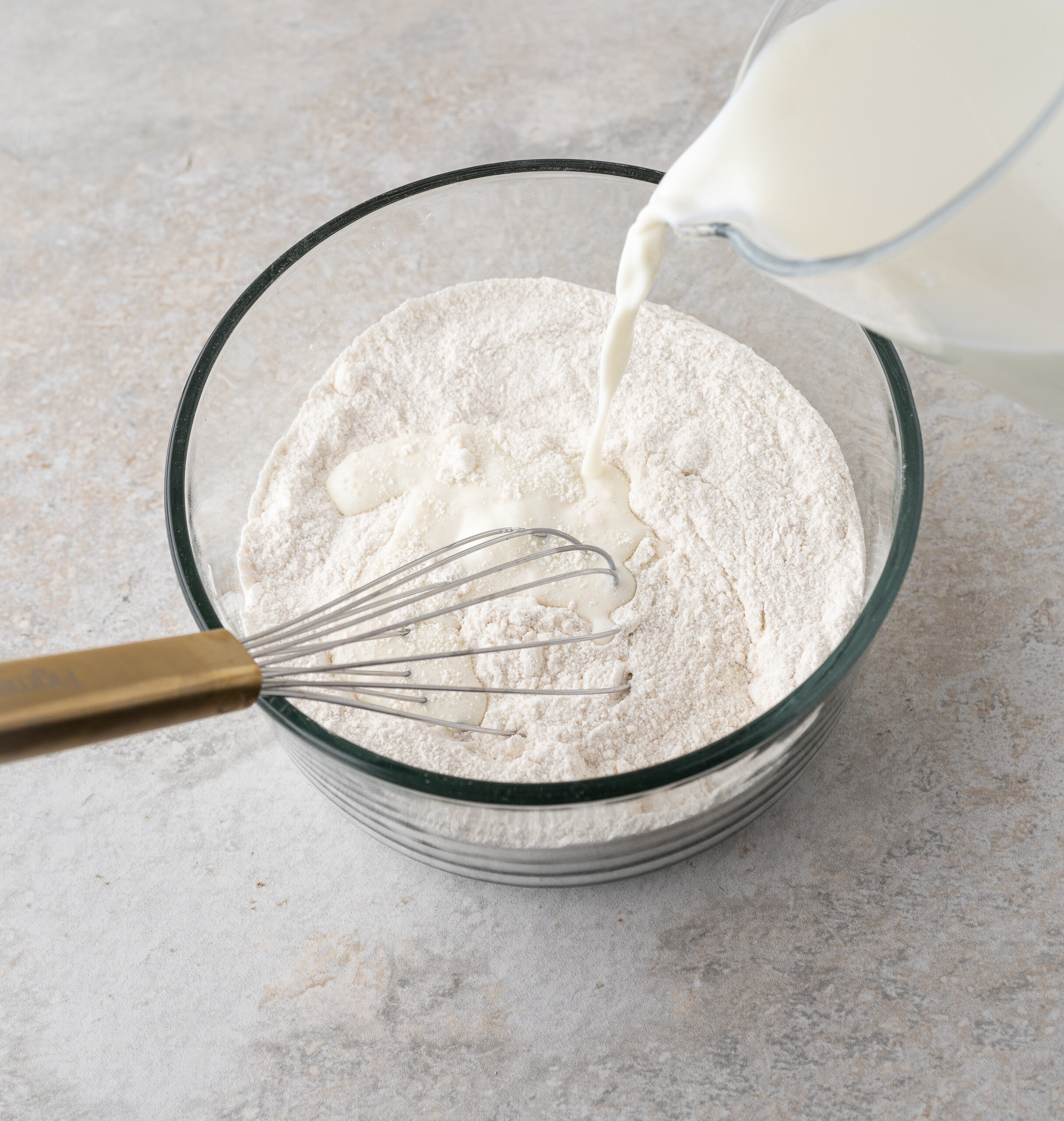Pouring milk into the dry ingredients to create the pecan pie cobbler batter