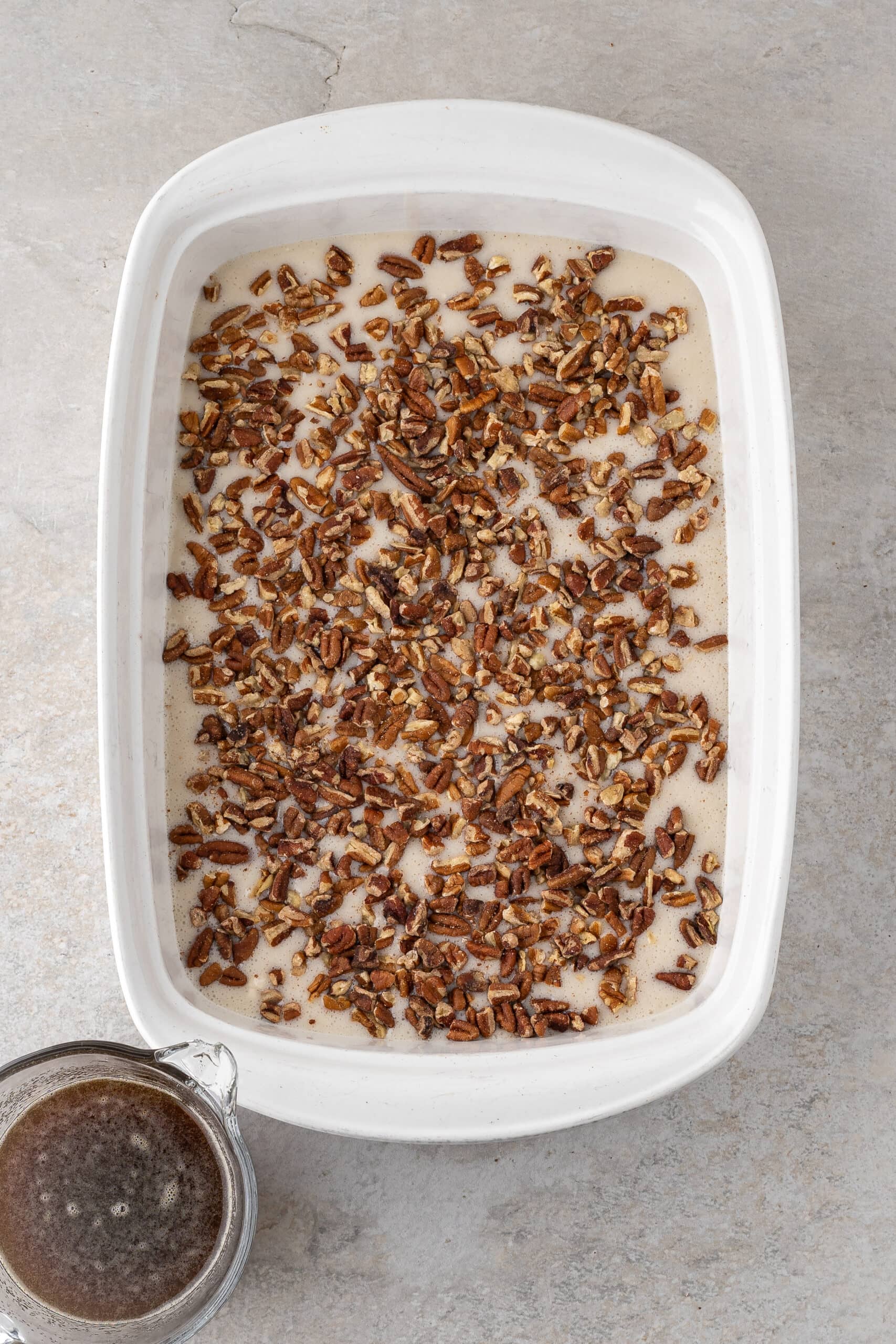 Caramel sauce is ready to be poured on top of pecan pie cobbler batter.