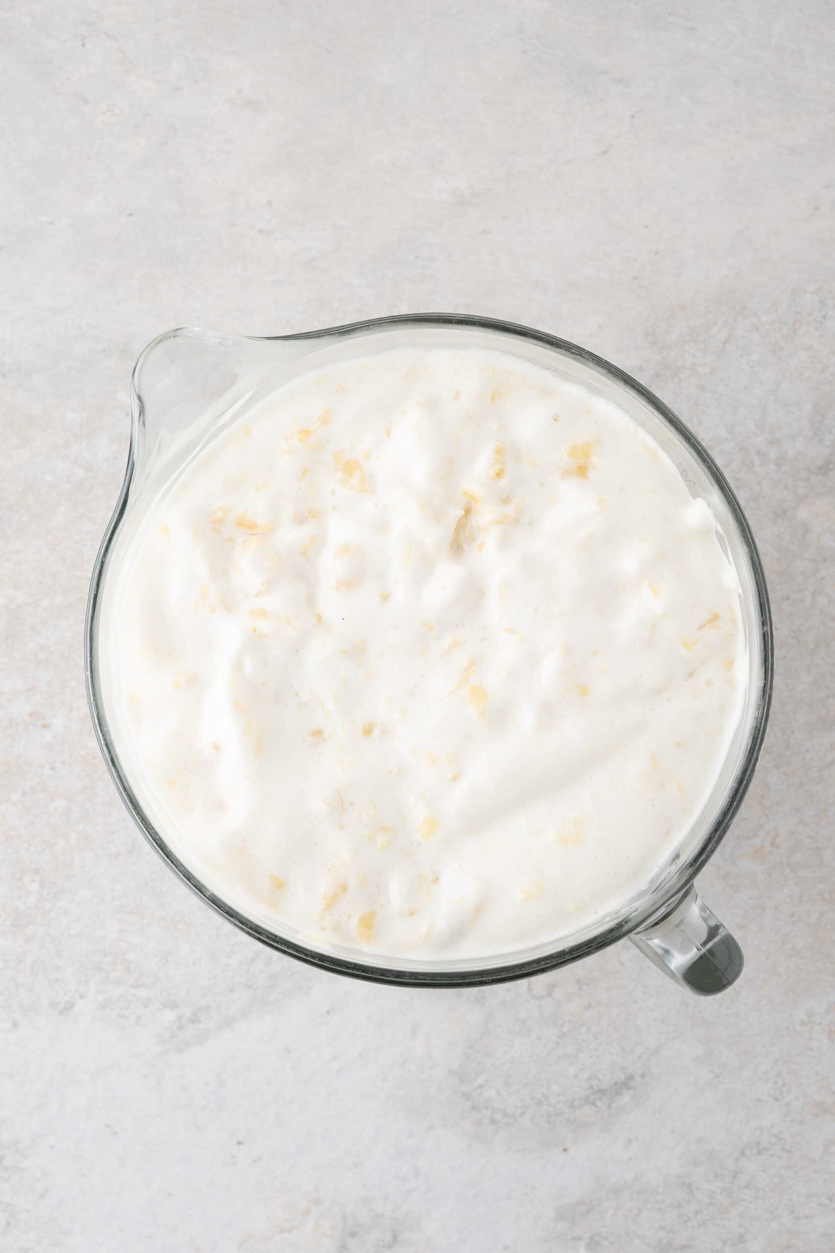 two ingredients: cake mix and crushed pineapple in a mixing bowl, getting ready to gently stir