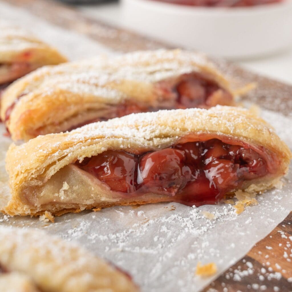Close up puff pastry with cherry pie filling drizzling out
