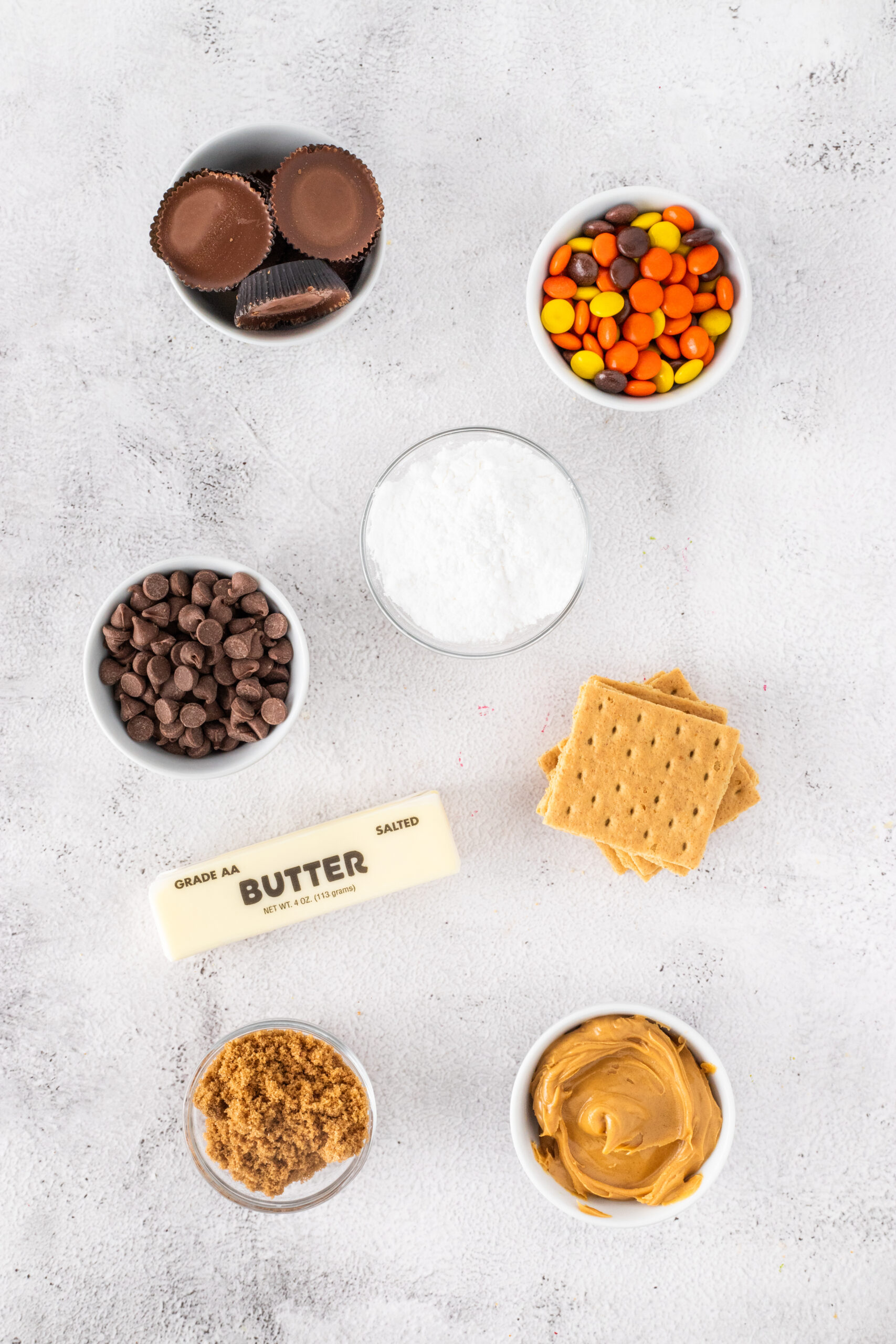 All ingredients to make Reese's no bake peanut butter bars:Reese's Peanut Butter Cups: graham crackers, melted salted butter, confectioners sugar, peanut butter, brown sugar, Reese's