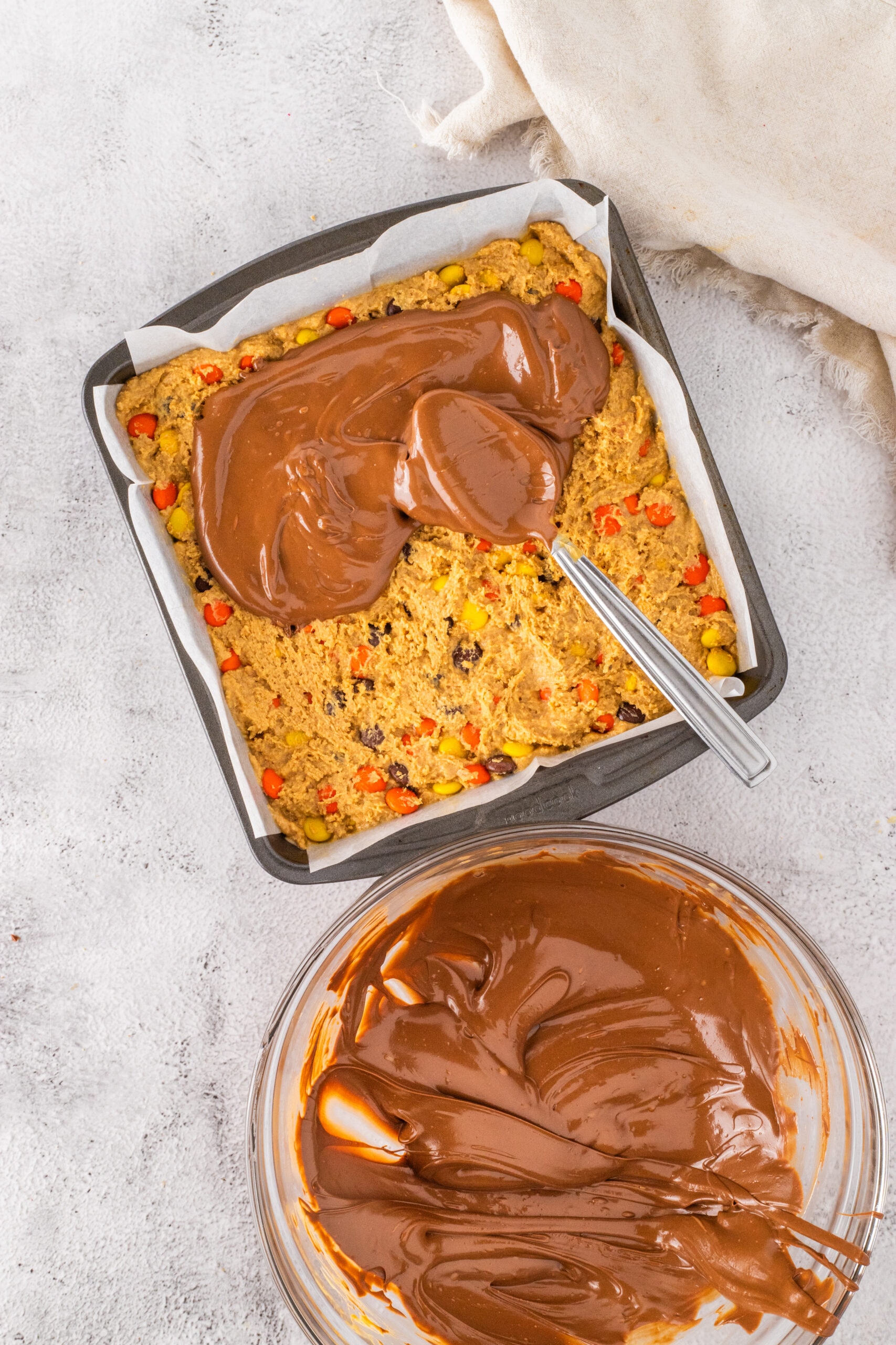 The process of pouring the Ganache over the bars and spreading it out evenly.