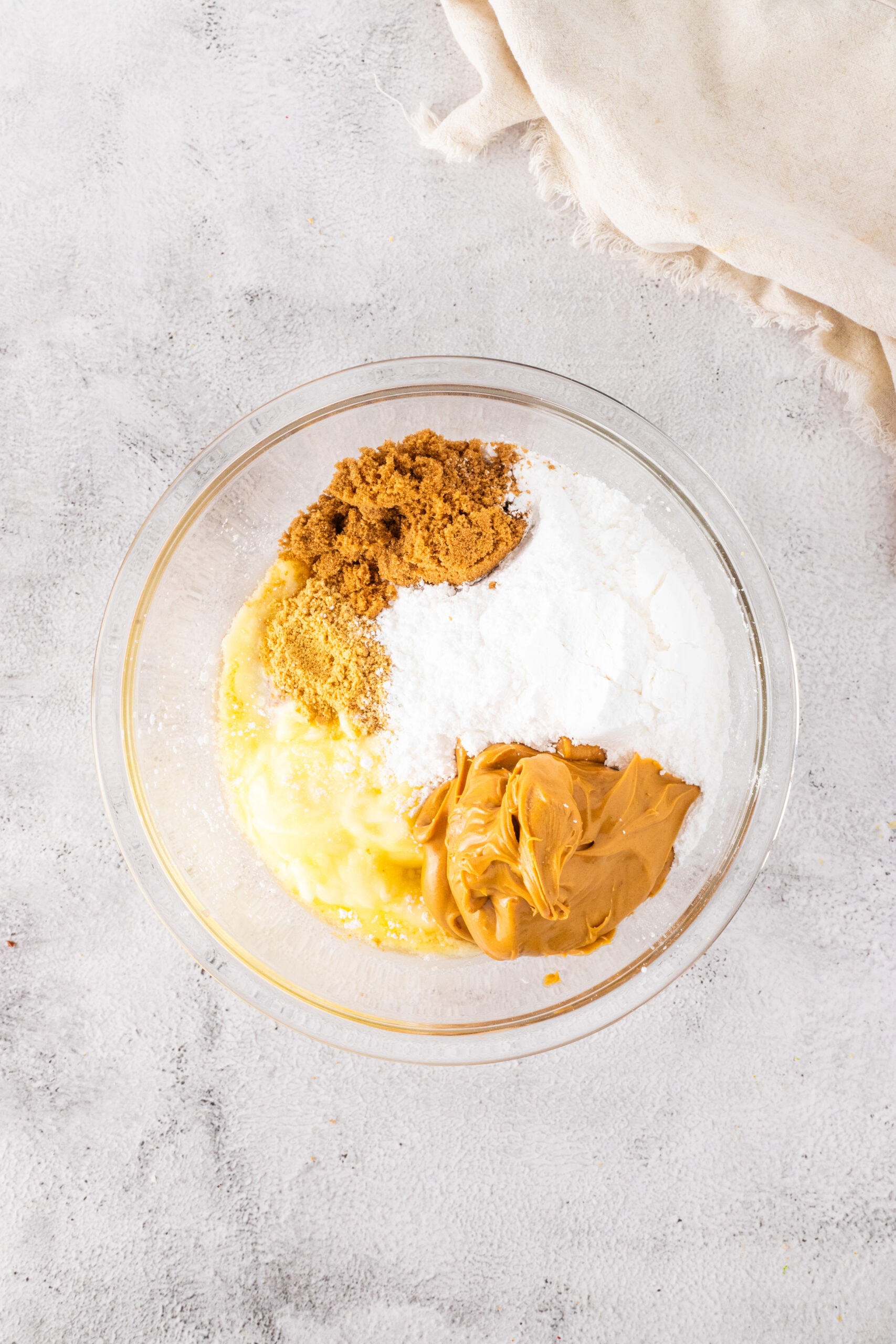 In a large mixing bowl, it's the process of adding the Graham Cracker crumbs, melted Butter, Confectioners' Sugar, Peanut Butter, and Brown Sugar.