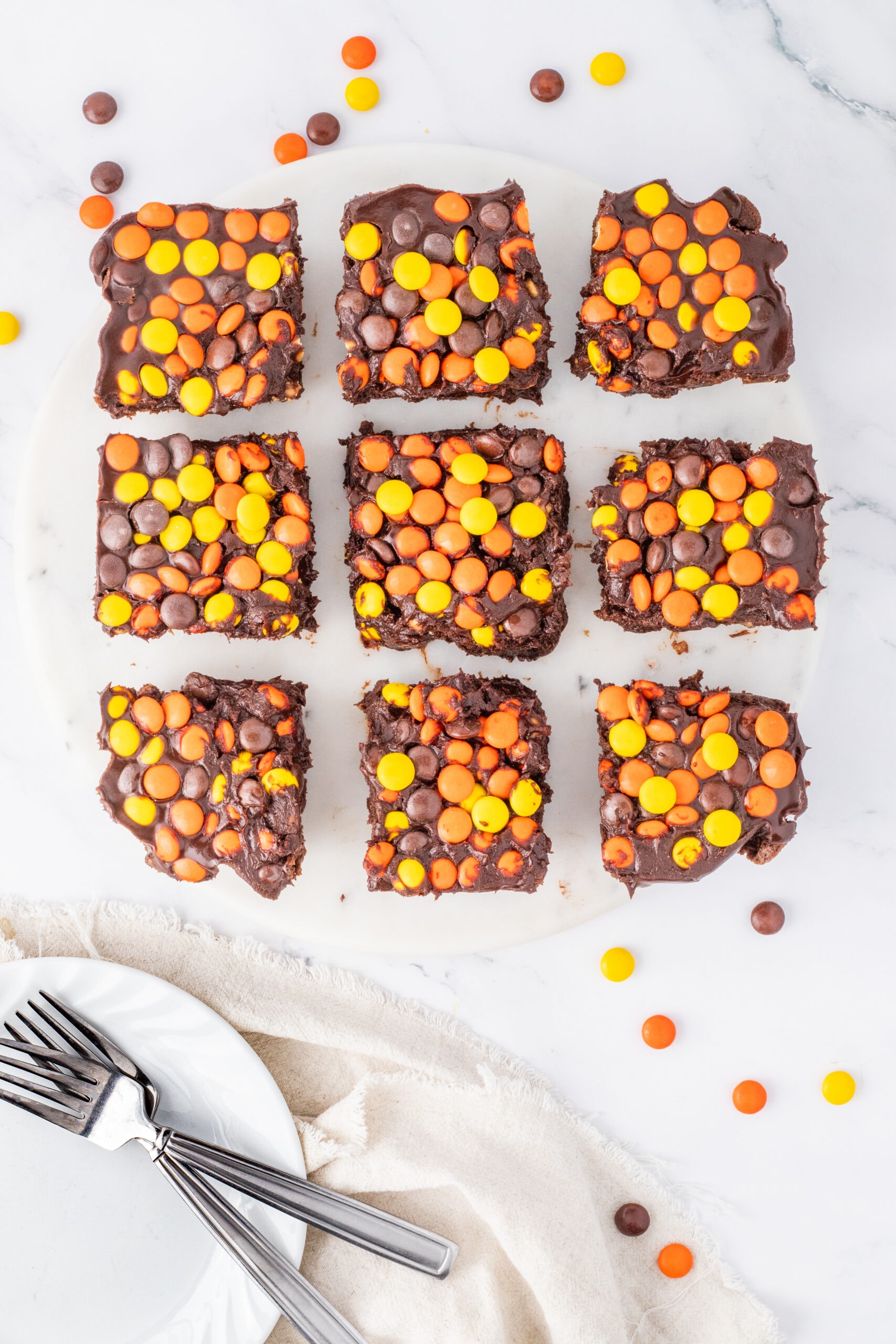 Reese's pieces brownies are cut in squares, plates and forks to the side to start to enjoy