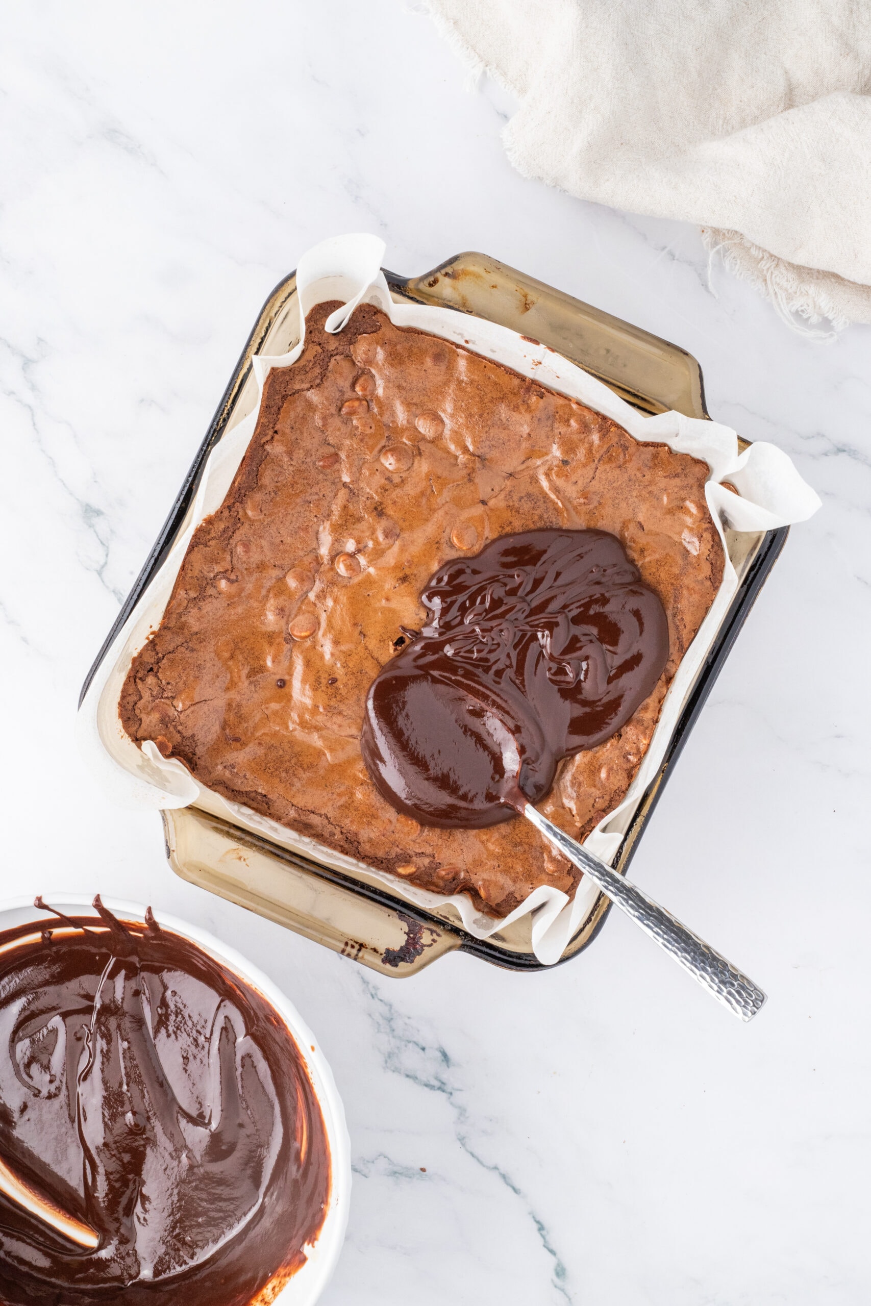 Spoonful of ganache is placed on top of brownies