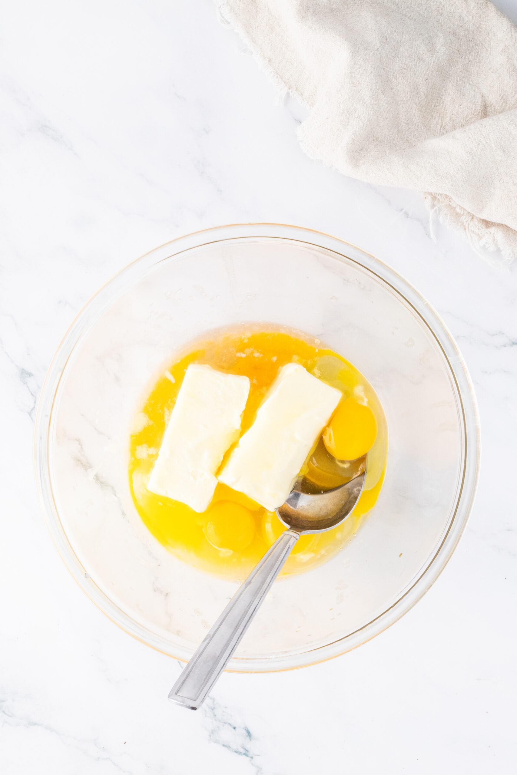 Melted butter and egg and an egg yolk in bowl to start the brownie process