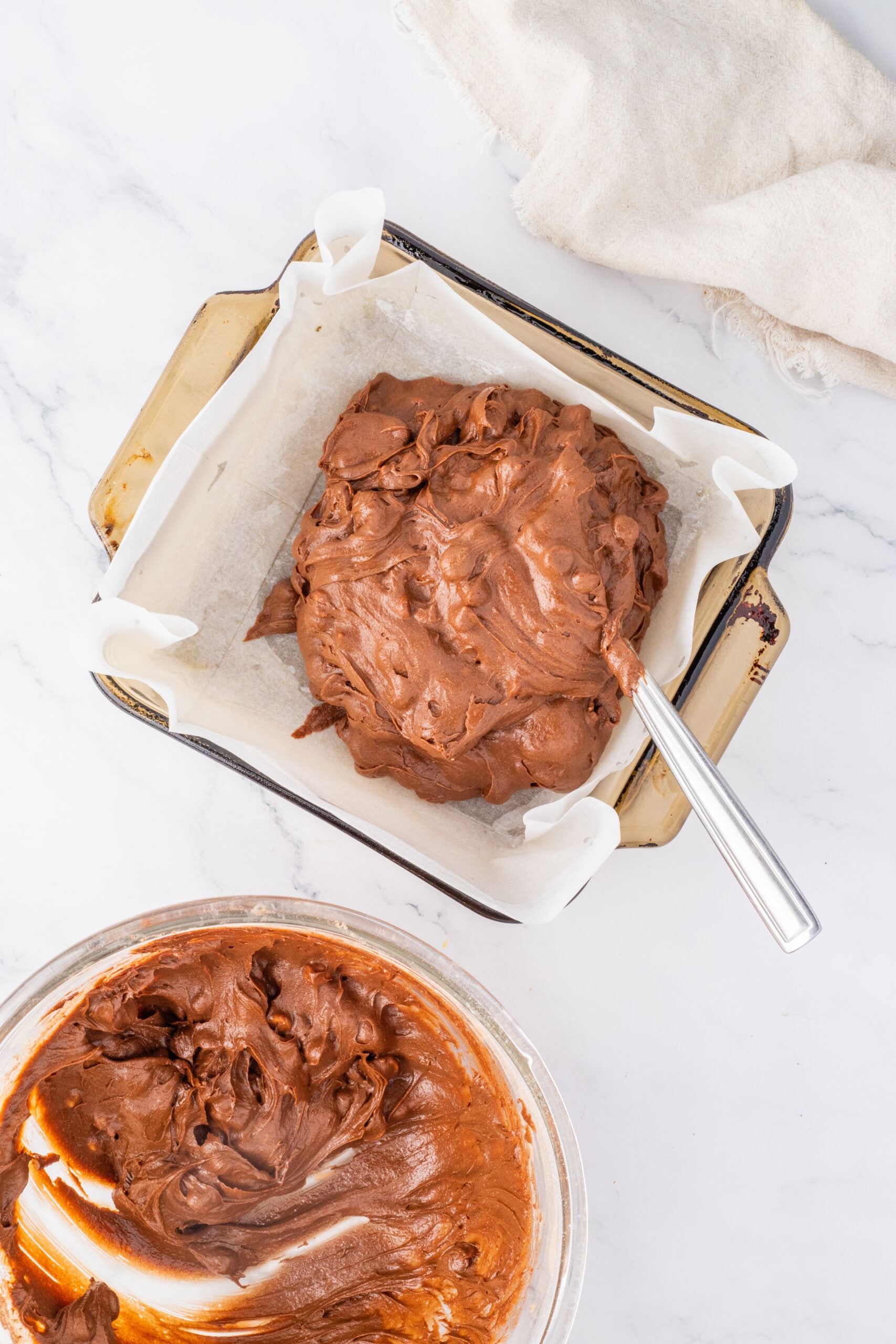 Brownie batter is being added to baking pan