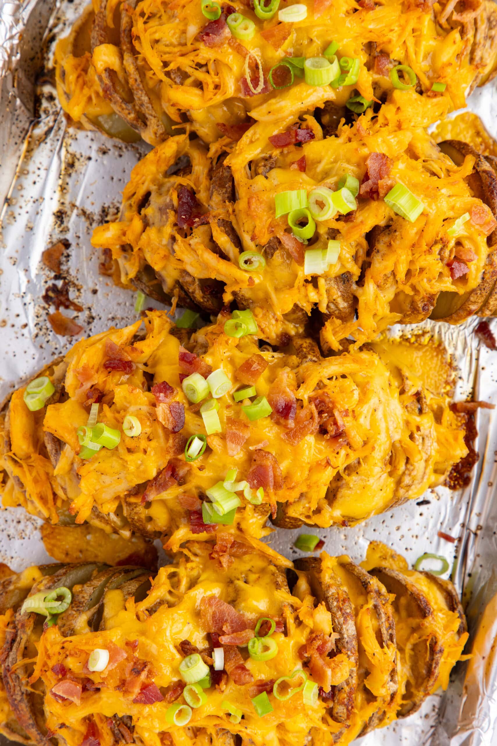 Four buffalo chicken stuffed potatoes on a baking sheet, cooling.