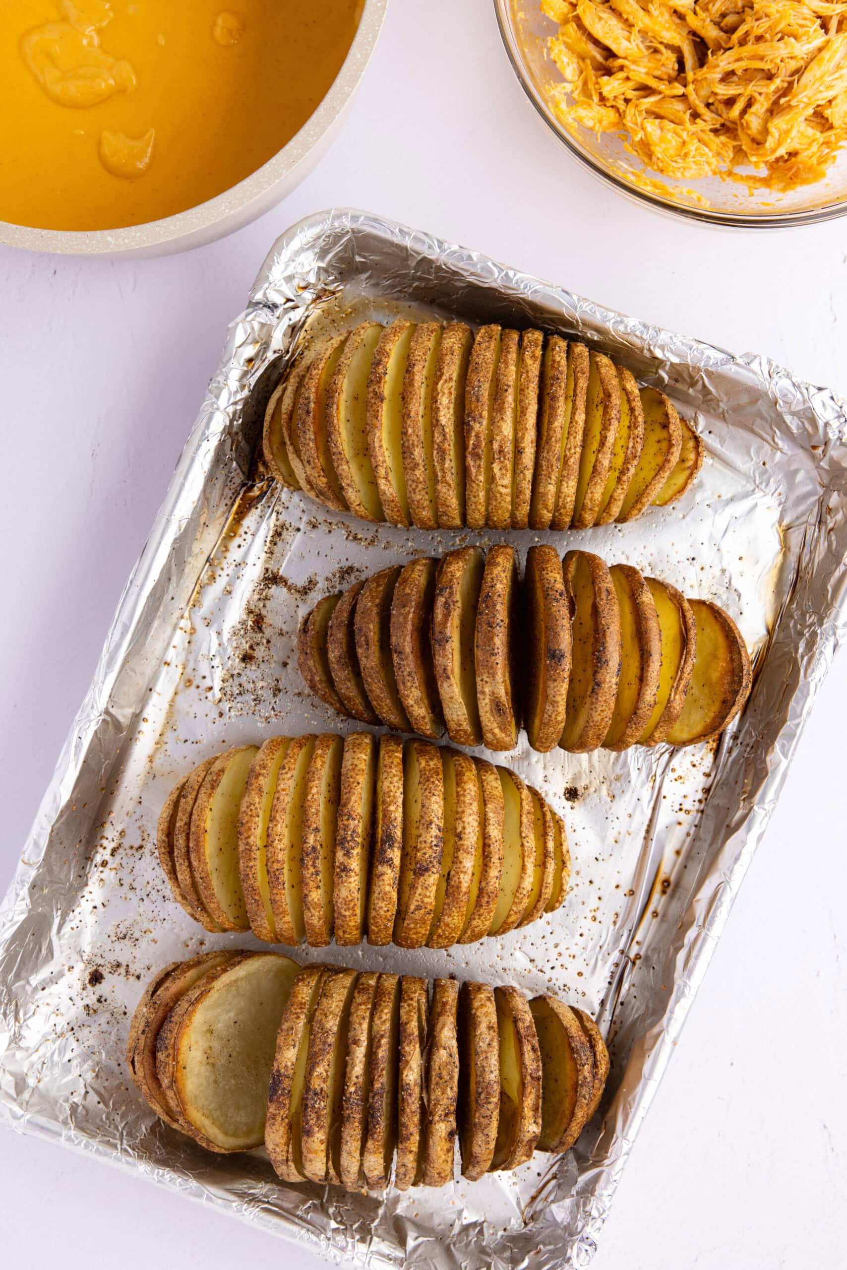 Adding oil, salt and pepper to the sliced potatoes