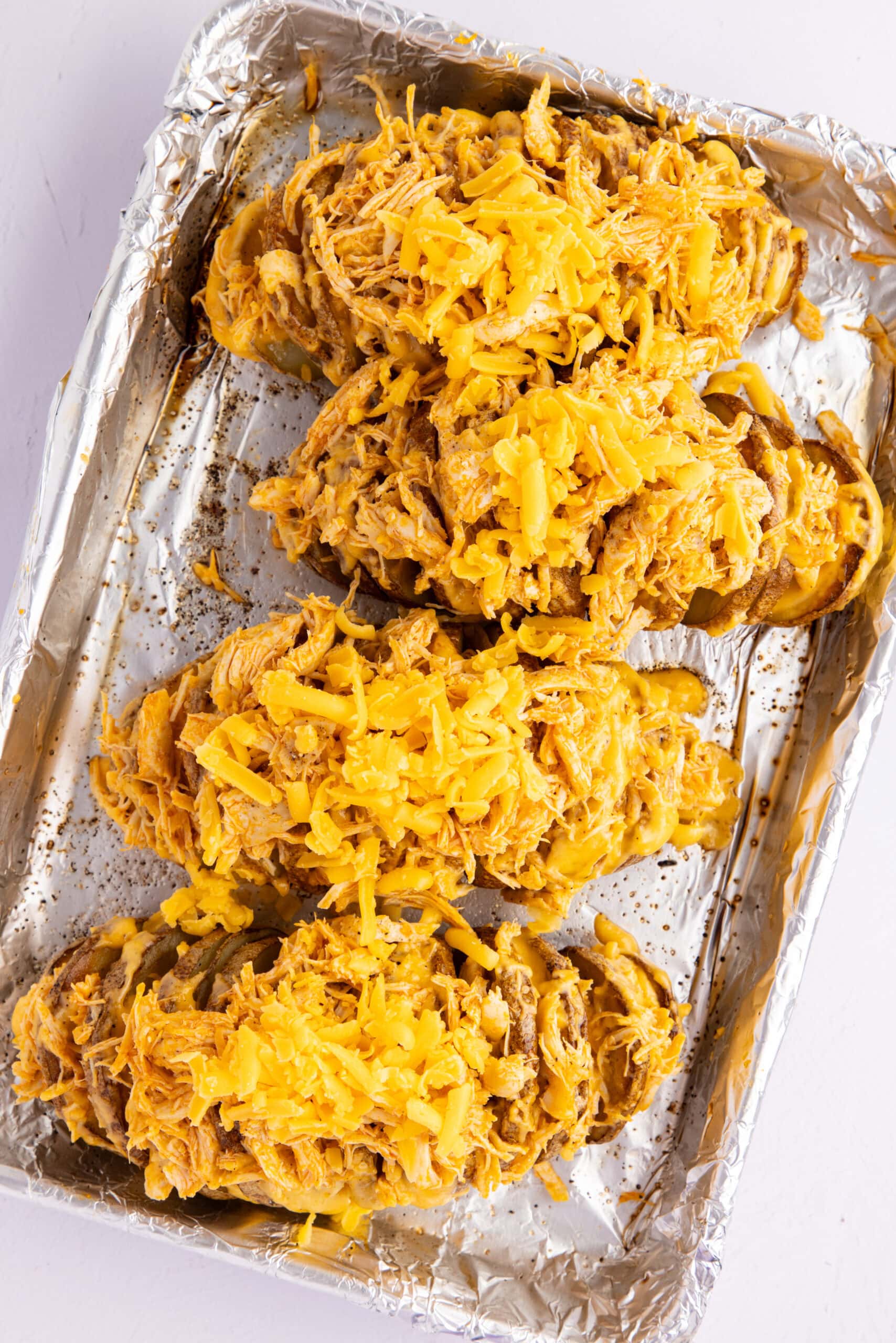Adding shredded cheese on top of stuffed potatoes