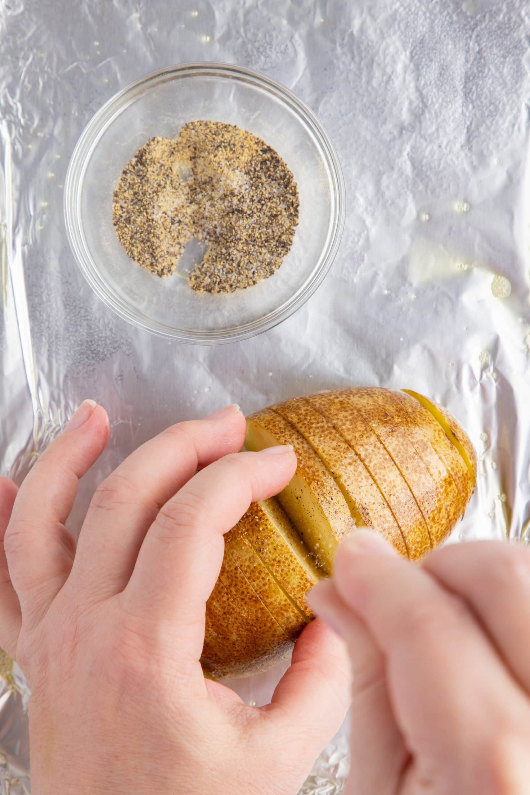 Adding oil and salt and pepper to each slice cut of the potatoes