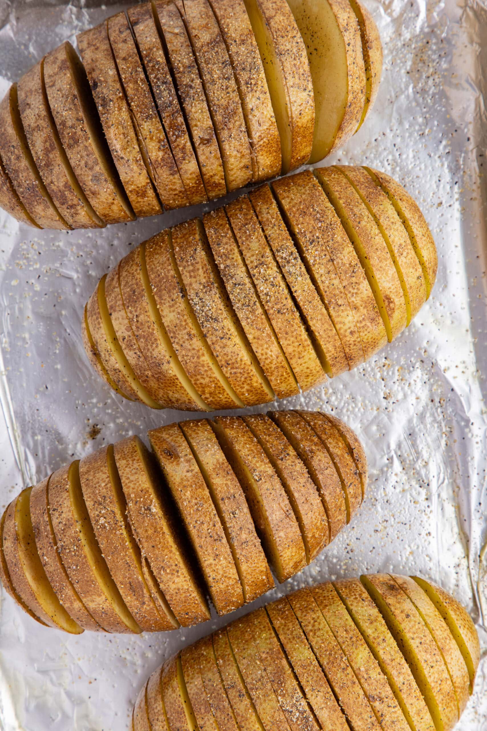 Sliced potatoes, adding oil and salt and pepper to the top of the potatoes